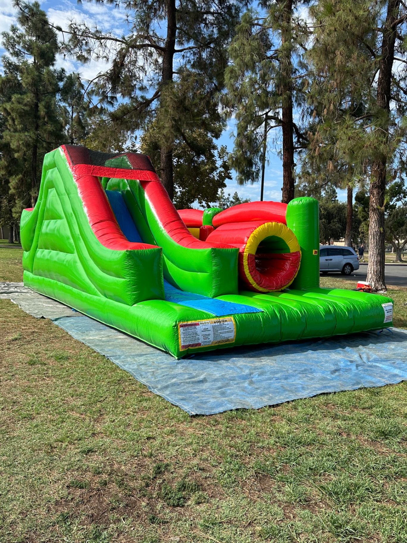 Challenge course obstacle rental in San Diego, green and red lane, wide three-quarter view of the full unit on a tarp at a park