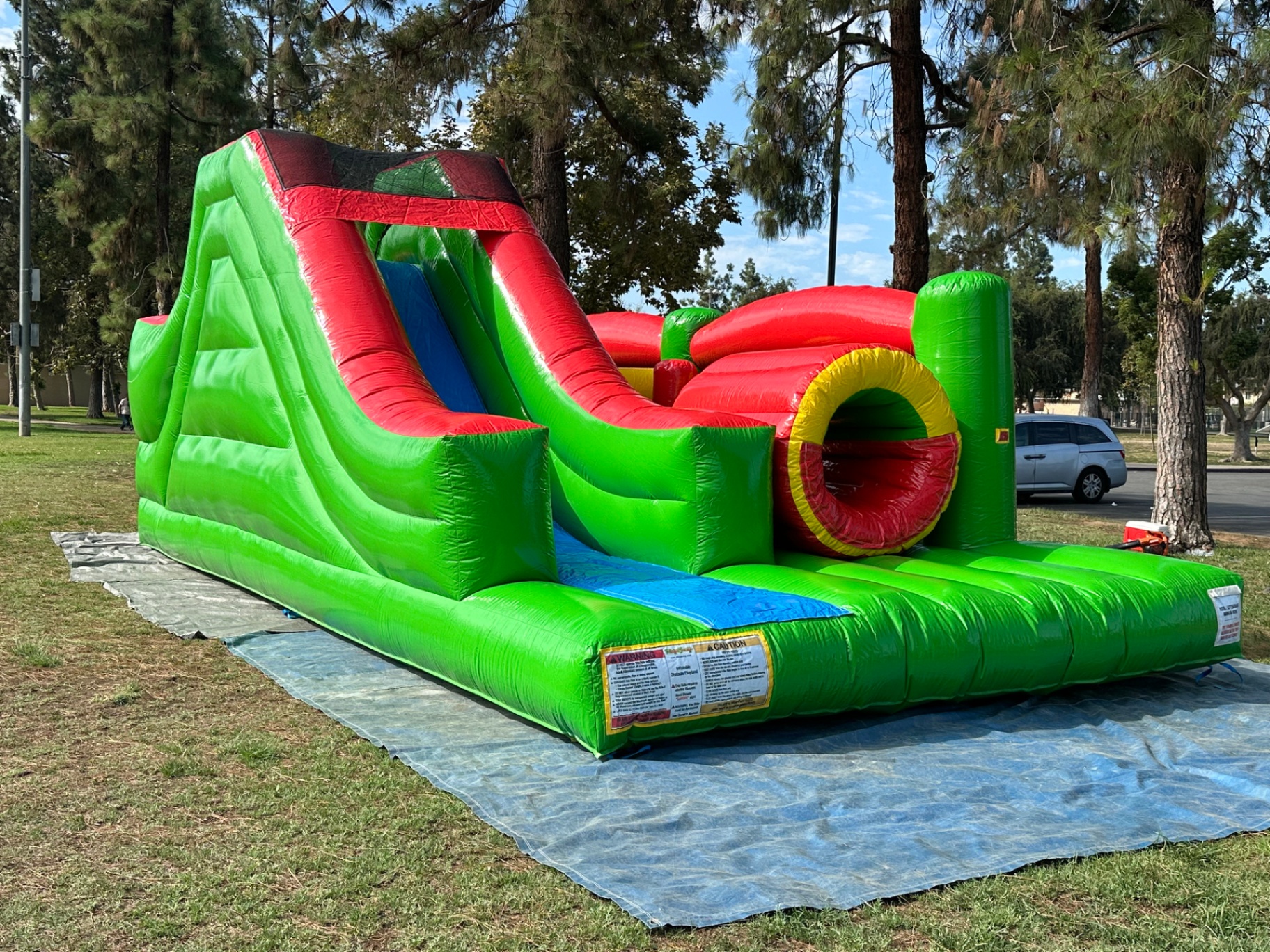 Challenge course obstacle rental in San Diego, green and red lane, angled view of the climb-and-slide tower beside the tunnel