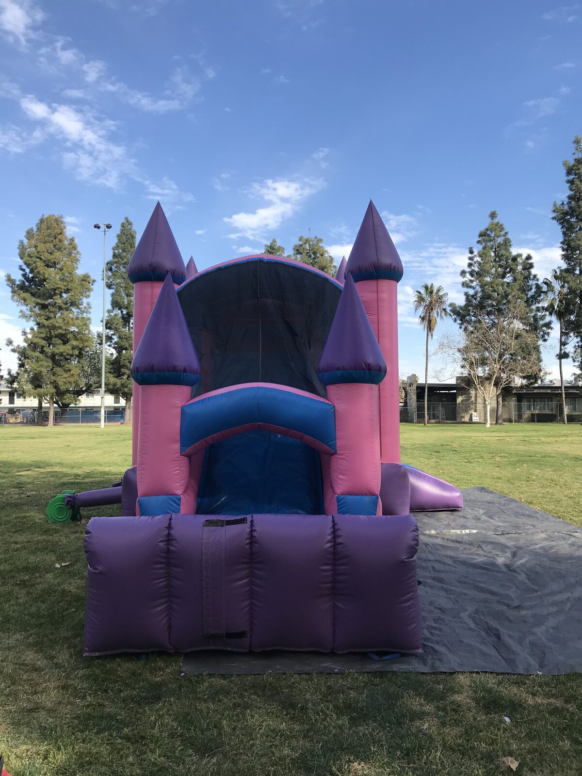 4n1 pink castle combo bounce house rental in San Diego, head-on view of the slide exit framed by purple-topped towers