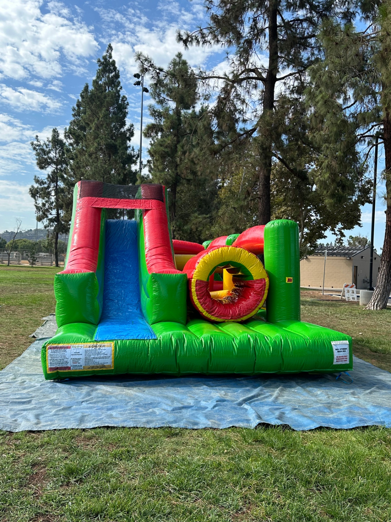 Challenge course obstacle rental in San Diego, green and red lane, straight-on front view of the blue slide and round tunnel