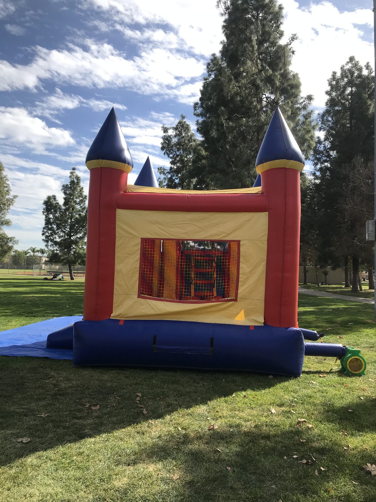 4n1 blue castle combo bounce house rental in San Diego, rear view of the yellow wall with mesh window and blower hooked up