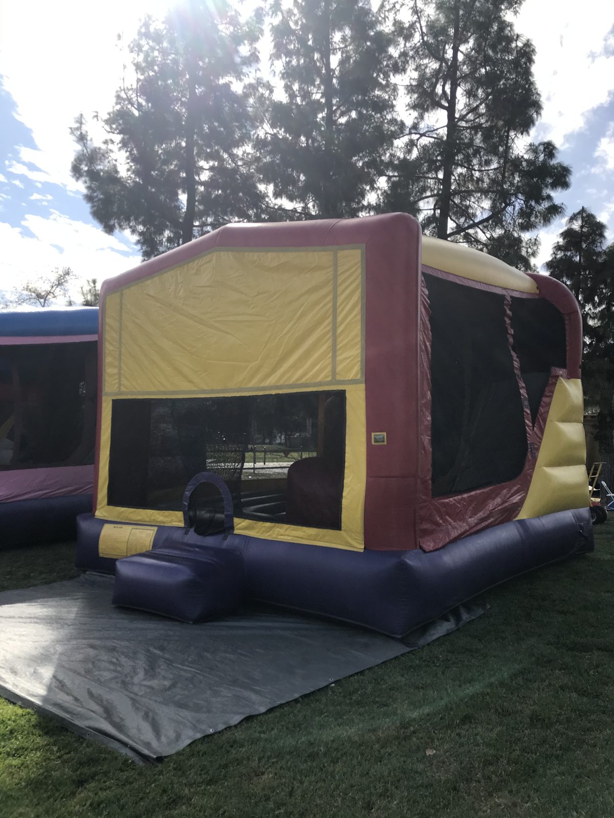 4n1 banner combo bounce house rental in San Diego, corner view showing the side mesh wall and slide on a tarp