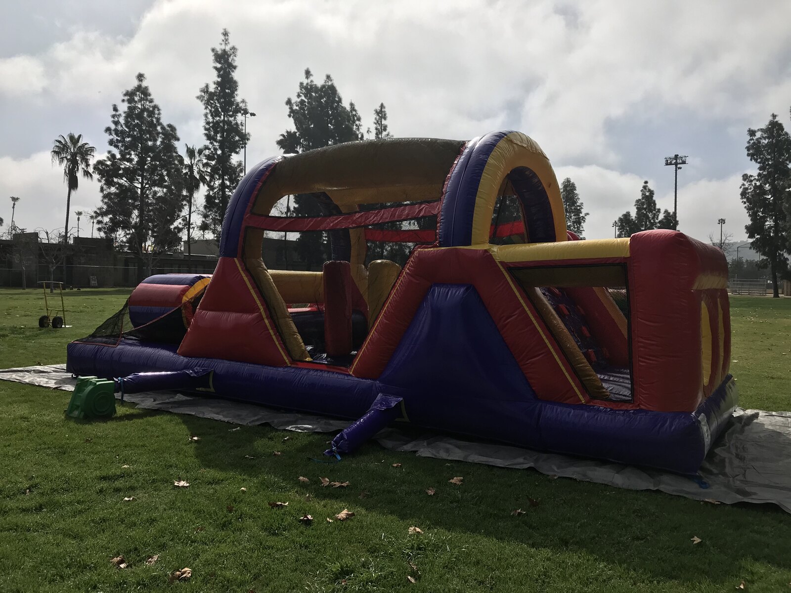 30ft backyard obstacle course rental in San Diego, angled three-quarter view of the whole course set up on grass over a protective tarp