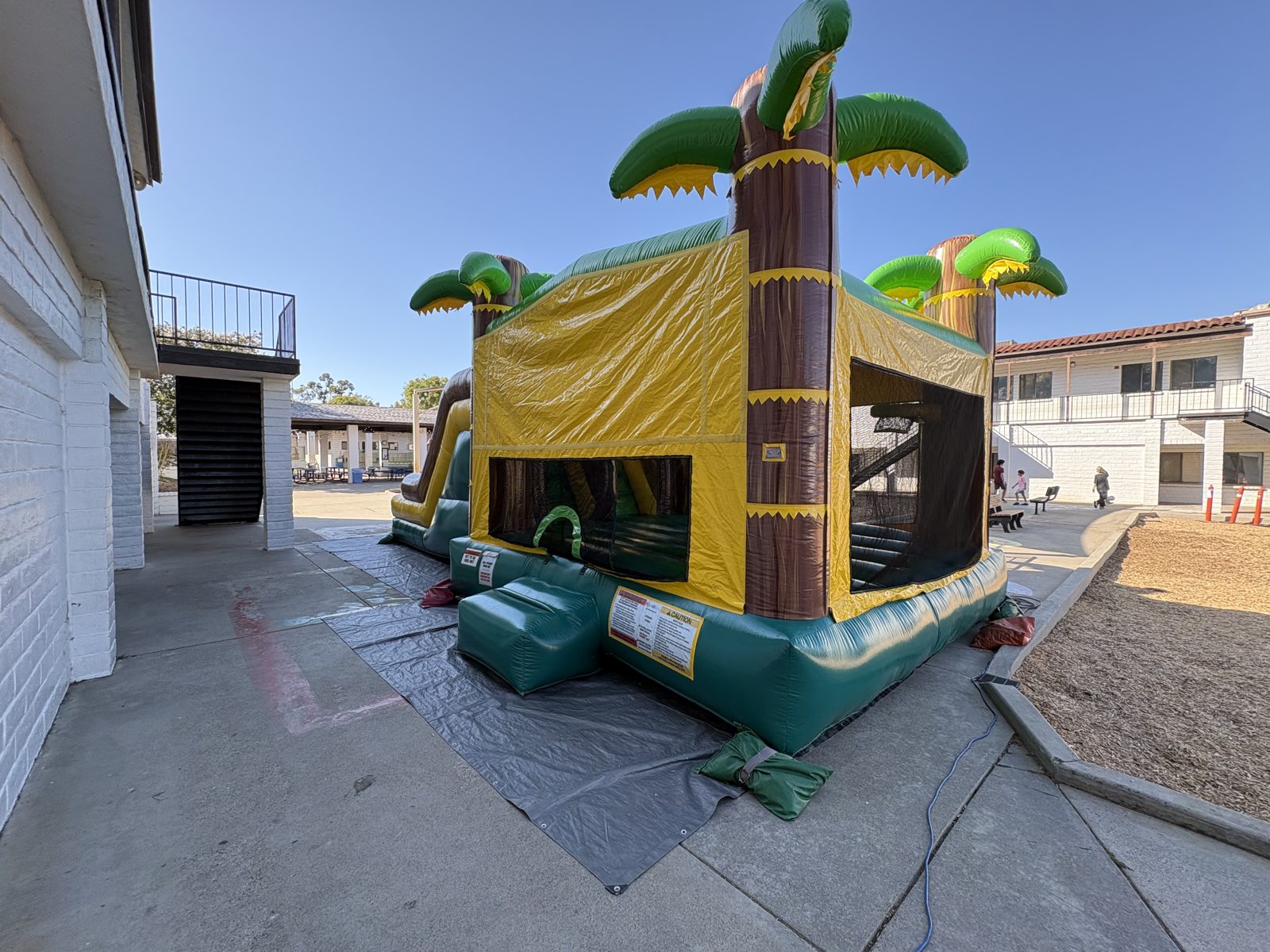4n1 tropical oasis dual slide combo bounce house rental in San Diego, corner view of the yellow walls, mesh windows and entry ramp