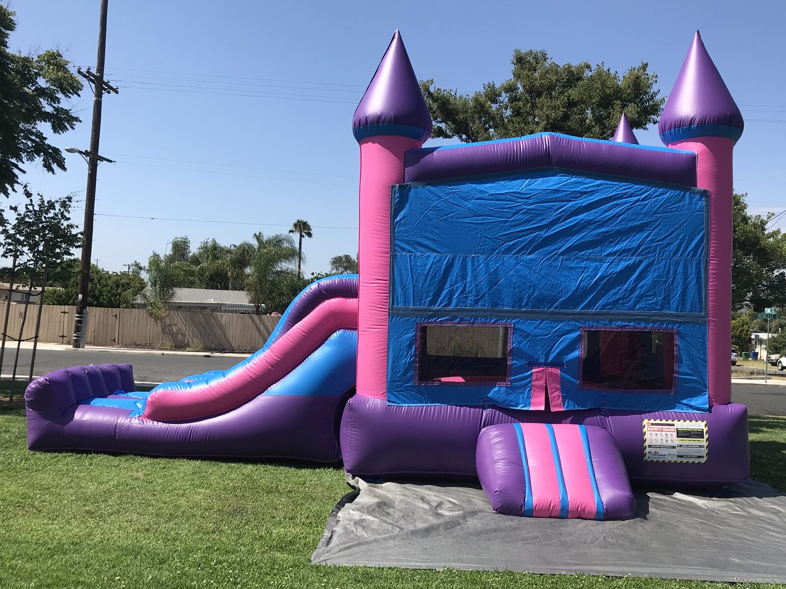 3n1 pink castle banner combo bounce house rental in San Diego, three-quarter view showing the purple turrets and step-up entry
