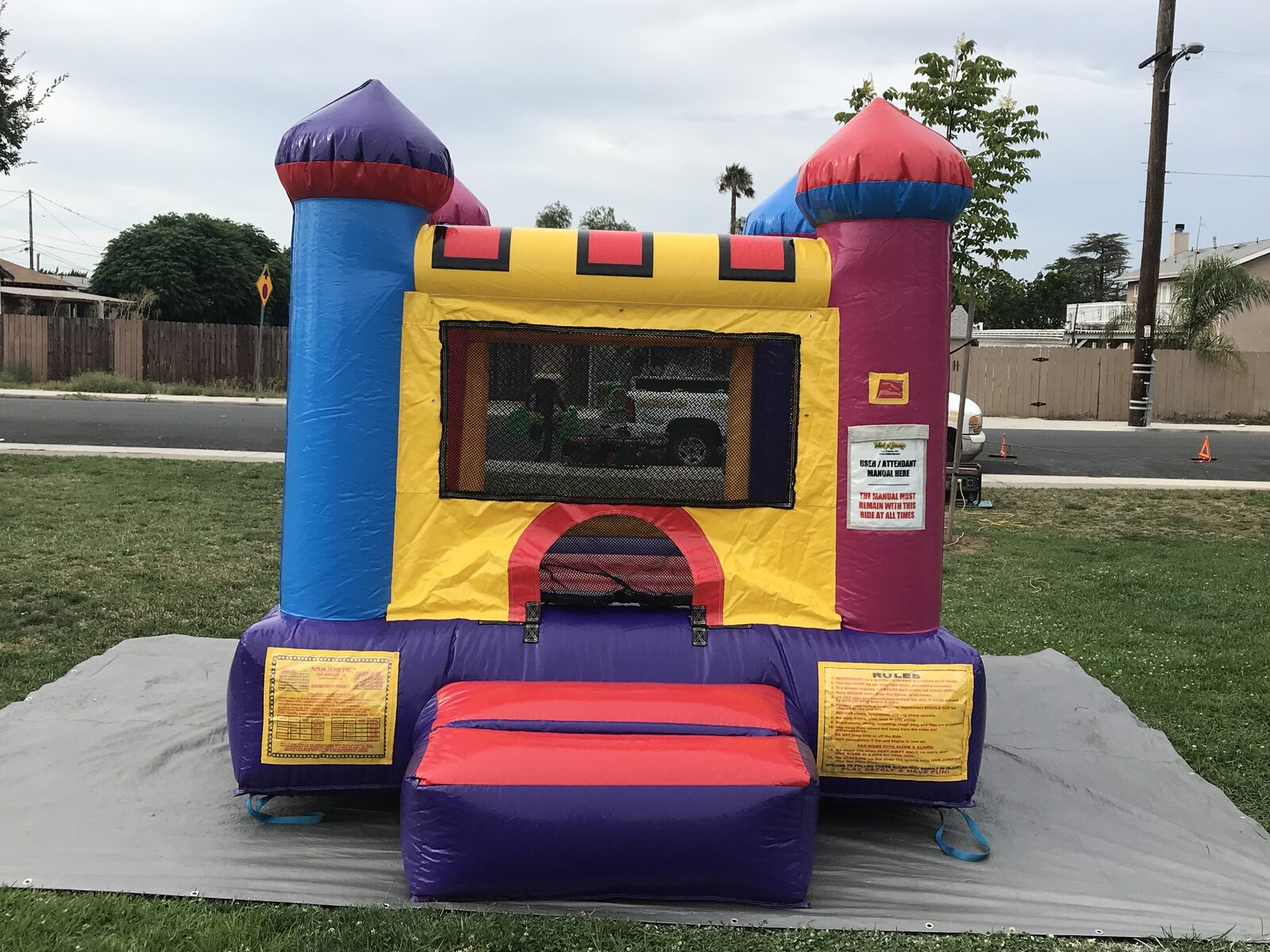 10x12 multi color castle mini bounce house rental in San Diego, straight-on front view of the arched entry and turret towers