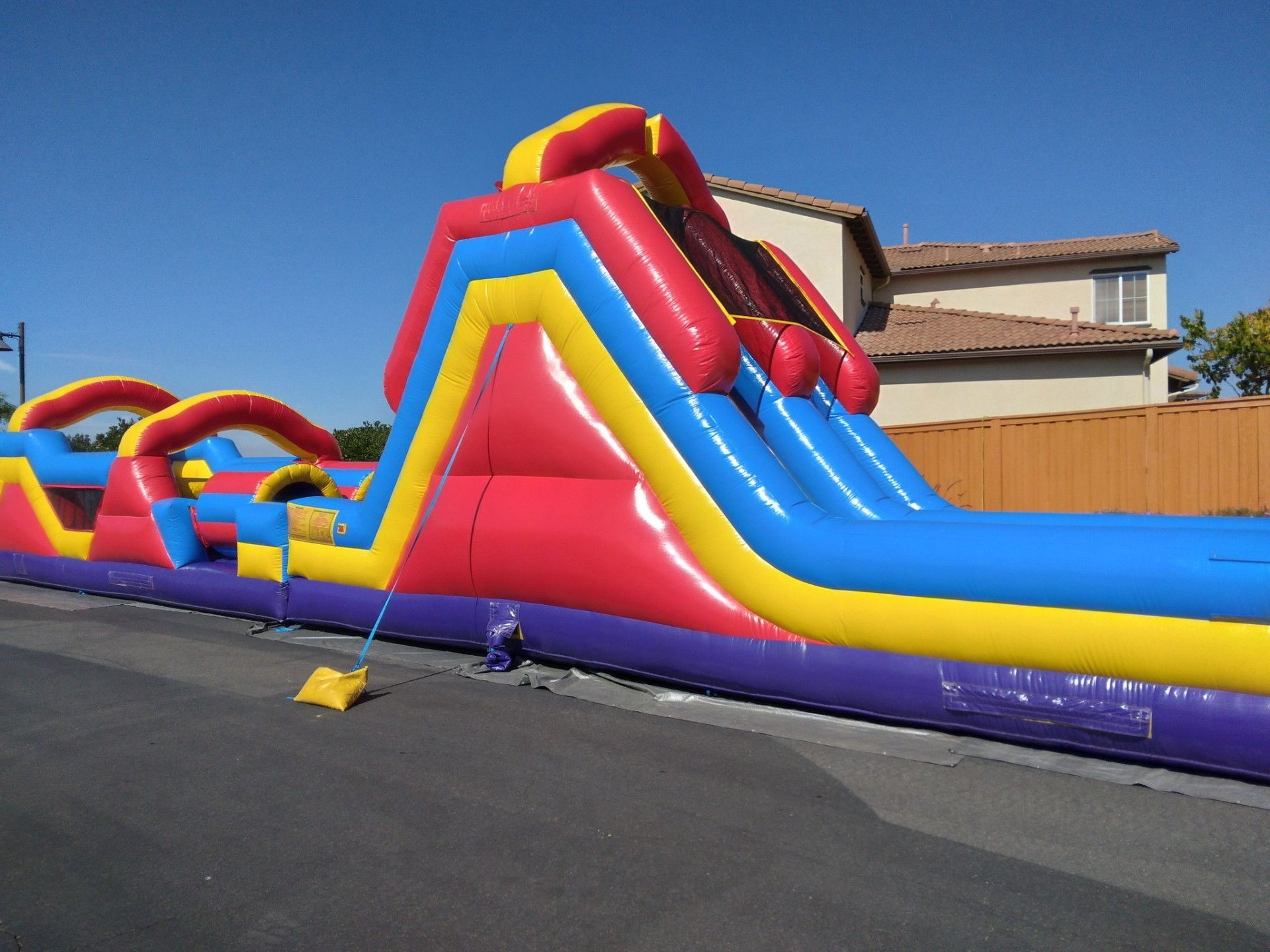 70ft monster obstacle course rental in San Diego, close side view of the slide tower with the obstacle lane running alongside