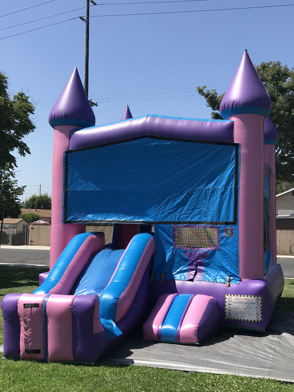2n1 pink castle banner combo bounce house rental in San Diego, angled front view with the safety rules placard and mesh entry window