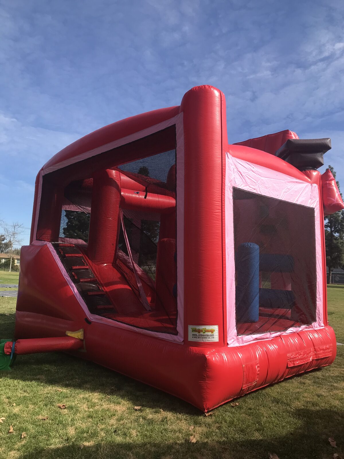 5n1 hello kitty combo bounce house rental in San Diego, rear view looking through the mesh at the interior climb-up, slide lane and obstacle columns