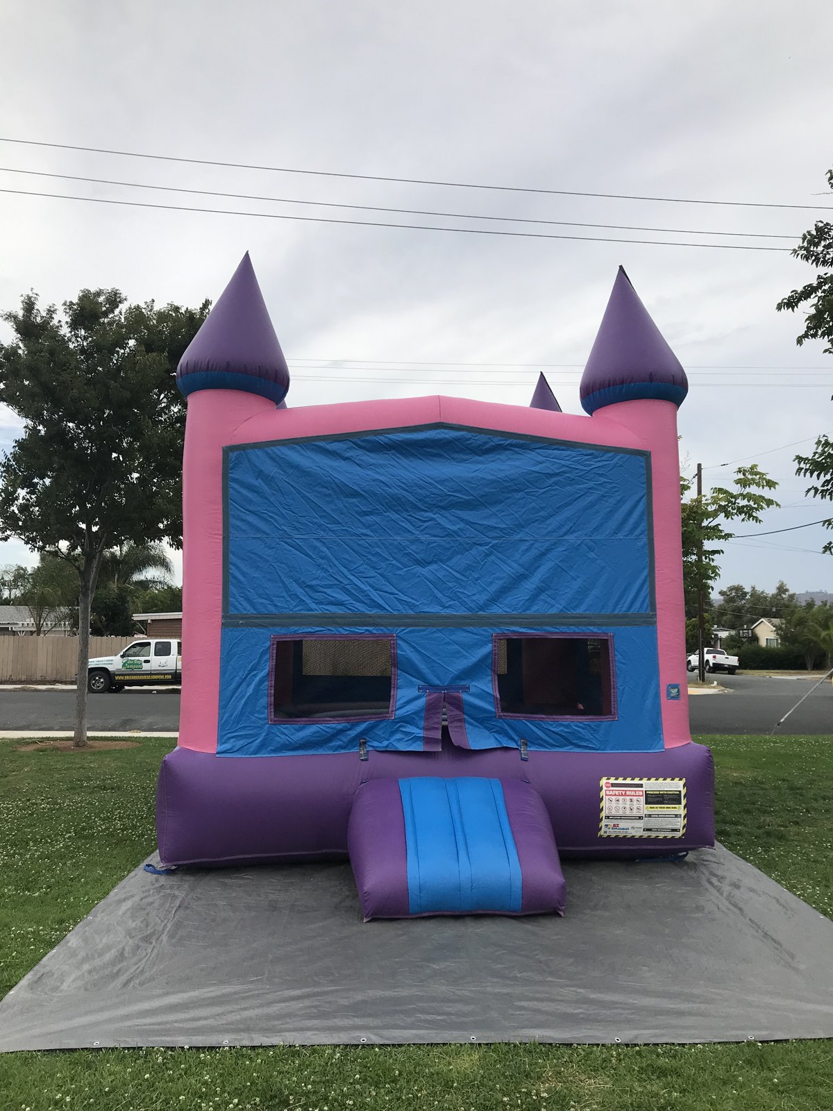 13x13 Pink Castle Banner bounce house rental in San Diego — front view with pink towers, purple turrets, and a blank blue banner panel ready for a custom theme