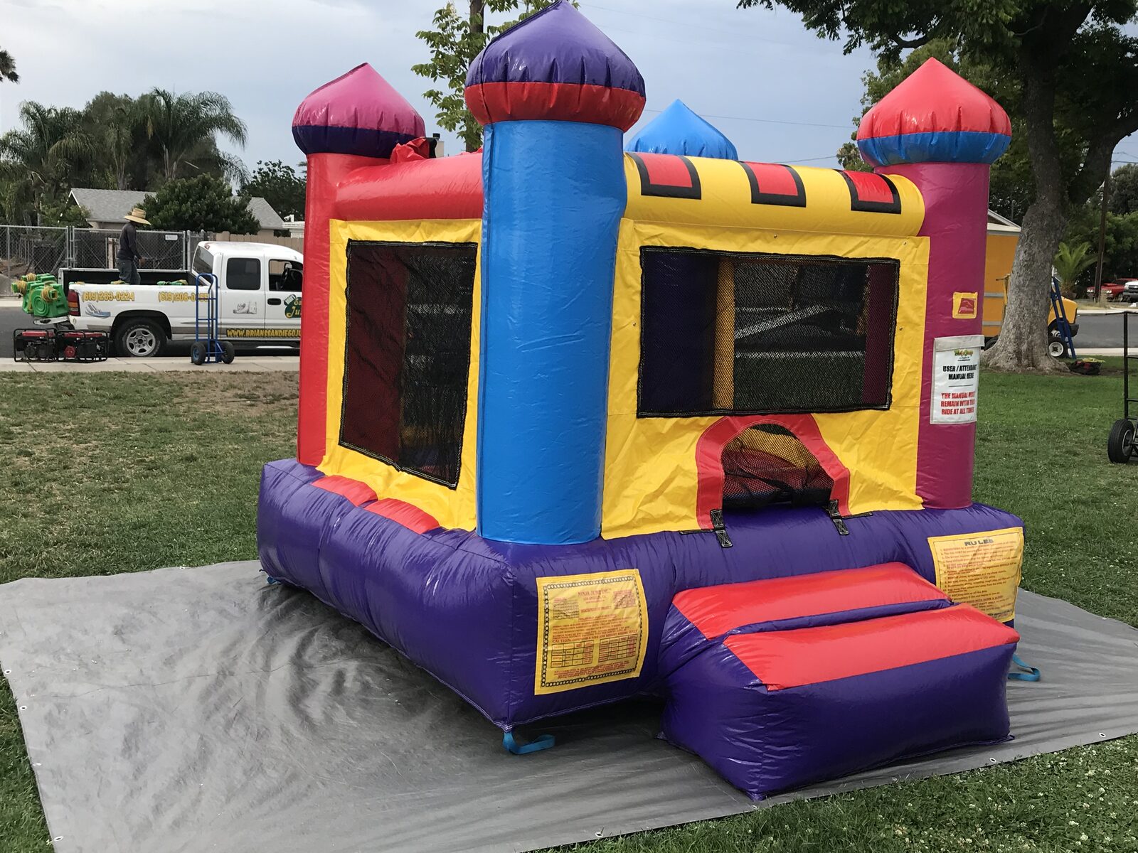 10x12 multi color castle mini bounce house rental in San Diego, angled view of the blue and red turrets and mesh side windows
