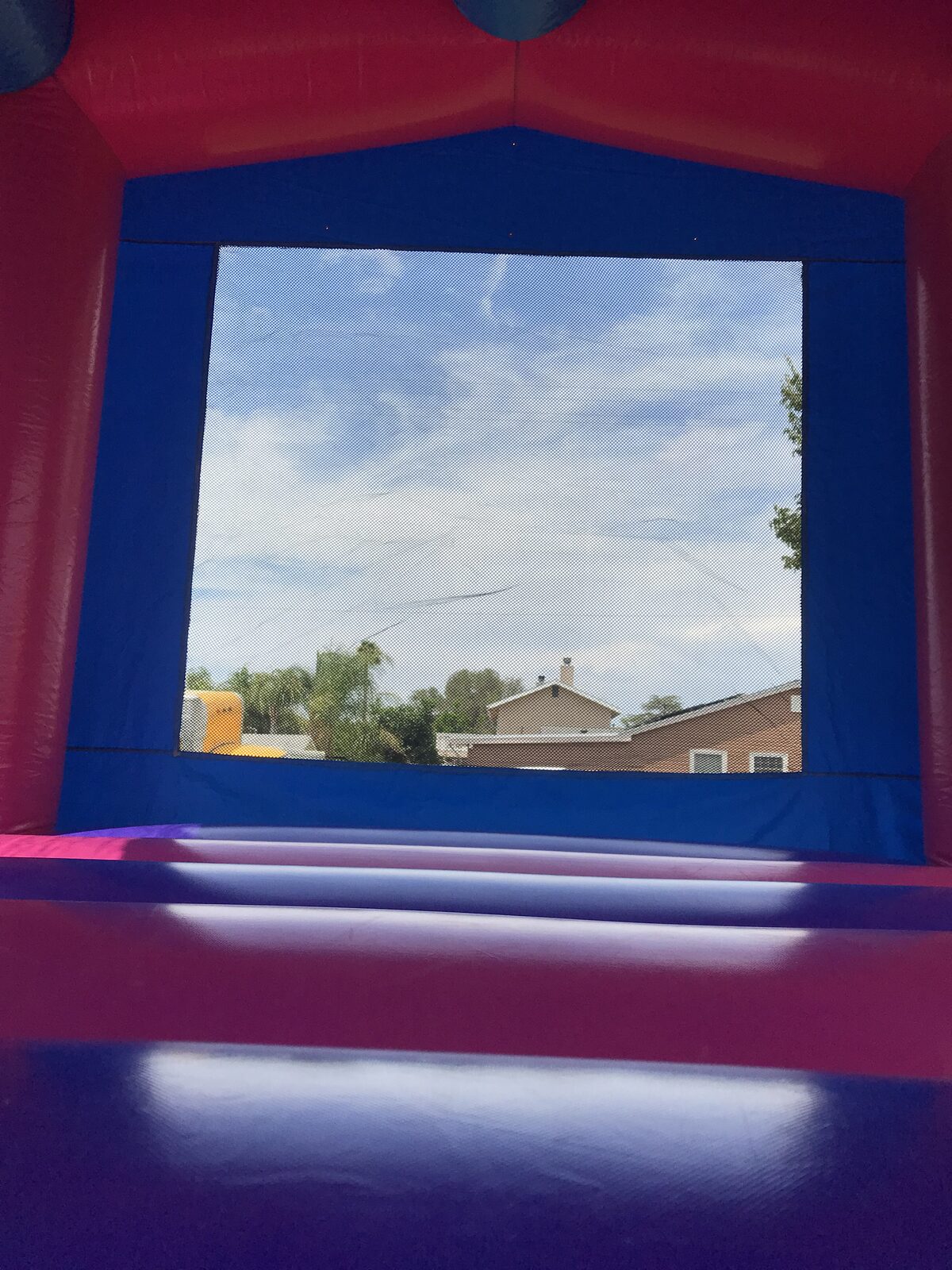 13x13 pink banner bounce house rental in San Diego — interior view looking out the mesh window from the jumping area