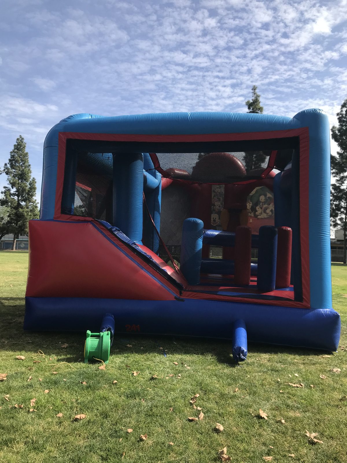 5n1 Mickey combo bounce house rental in San Diego, side view of the red slide and mesh-walled jump area
