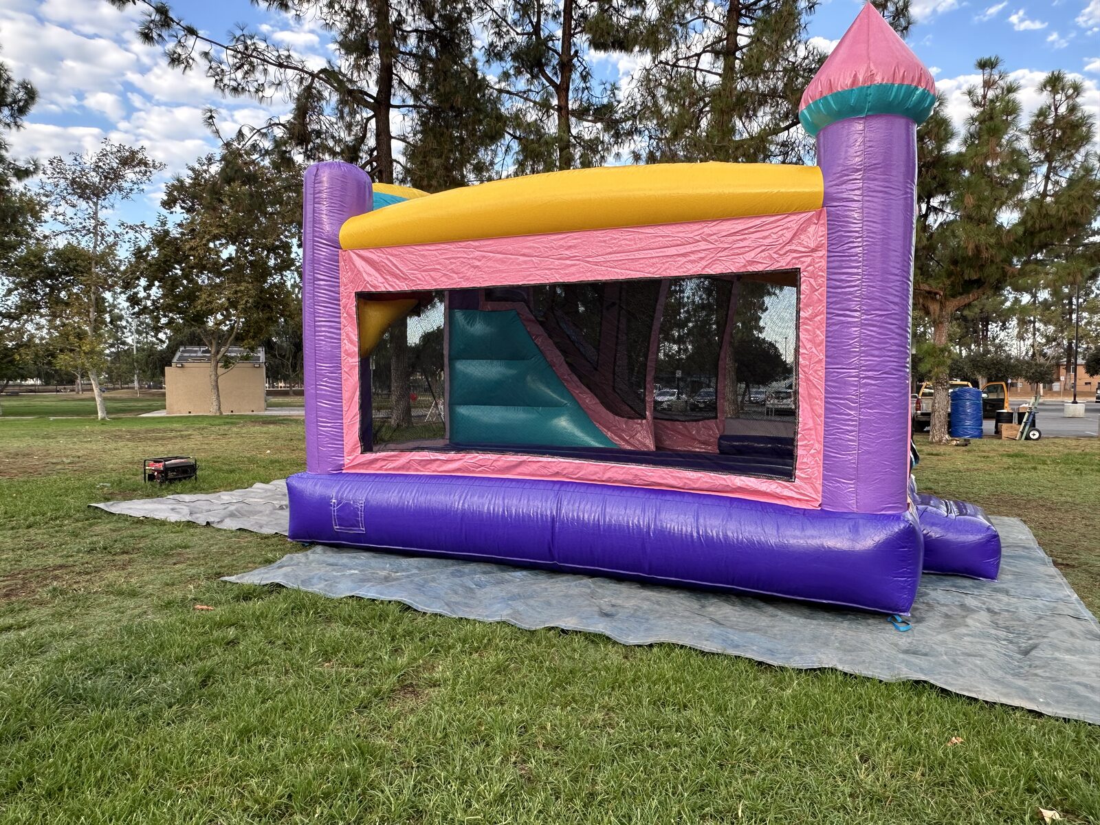 4n1 dazzling castle combo bounce house rental in San Diego, side view through the long mesh window showing the teal slide and climb-up inside