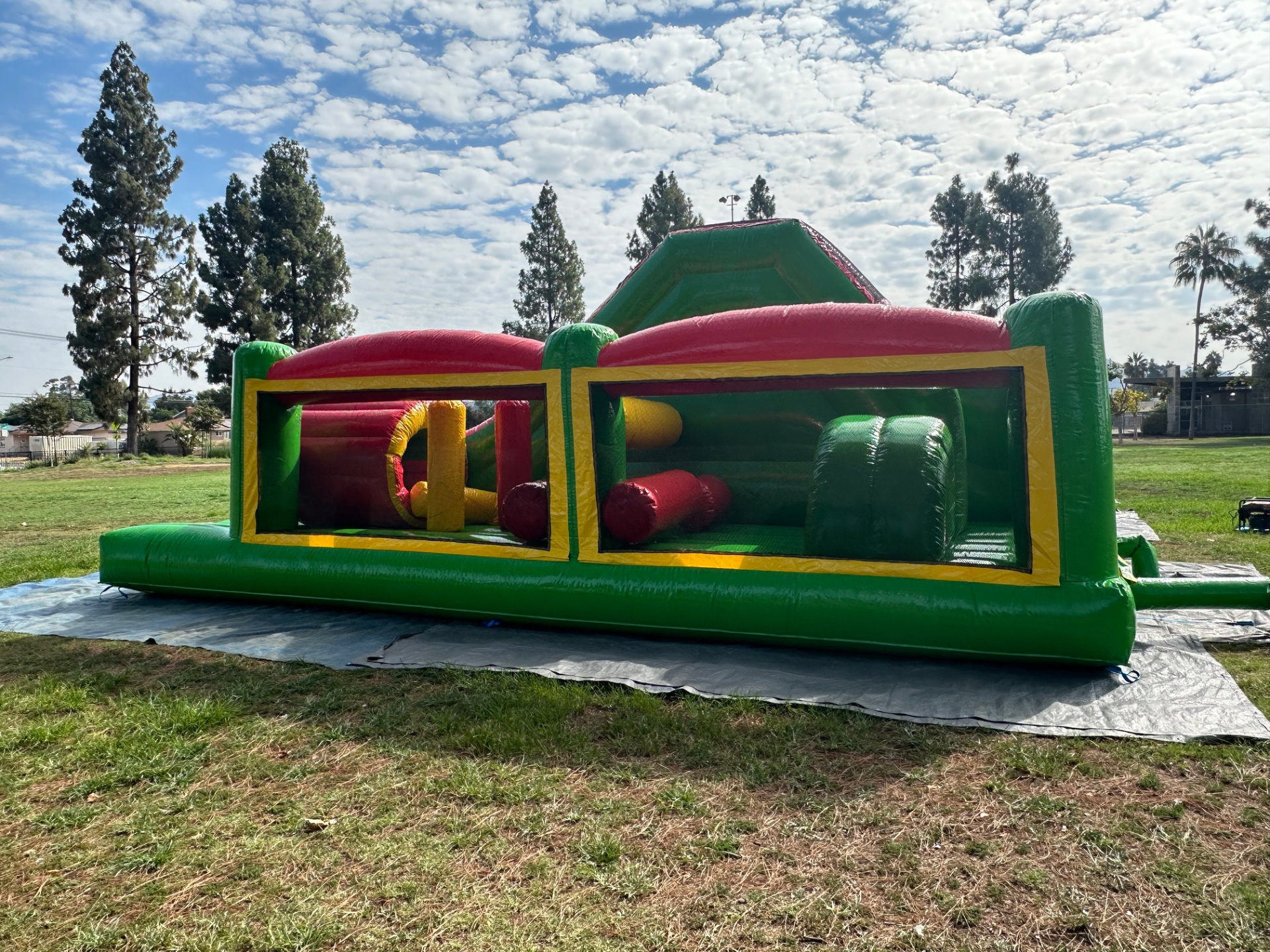 Challenge course obstacle rental in San Diego, green and red lane, side view through the mesh panels showing the pop-up obstacles inside