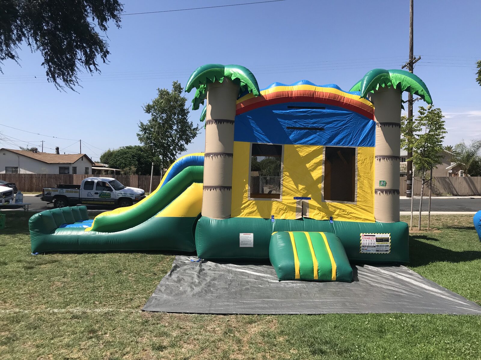 3n1 palm tree combo bounce house rental in San Diego, angled view of the dual slide lanes and green landing bumper