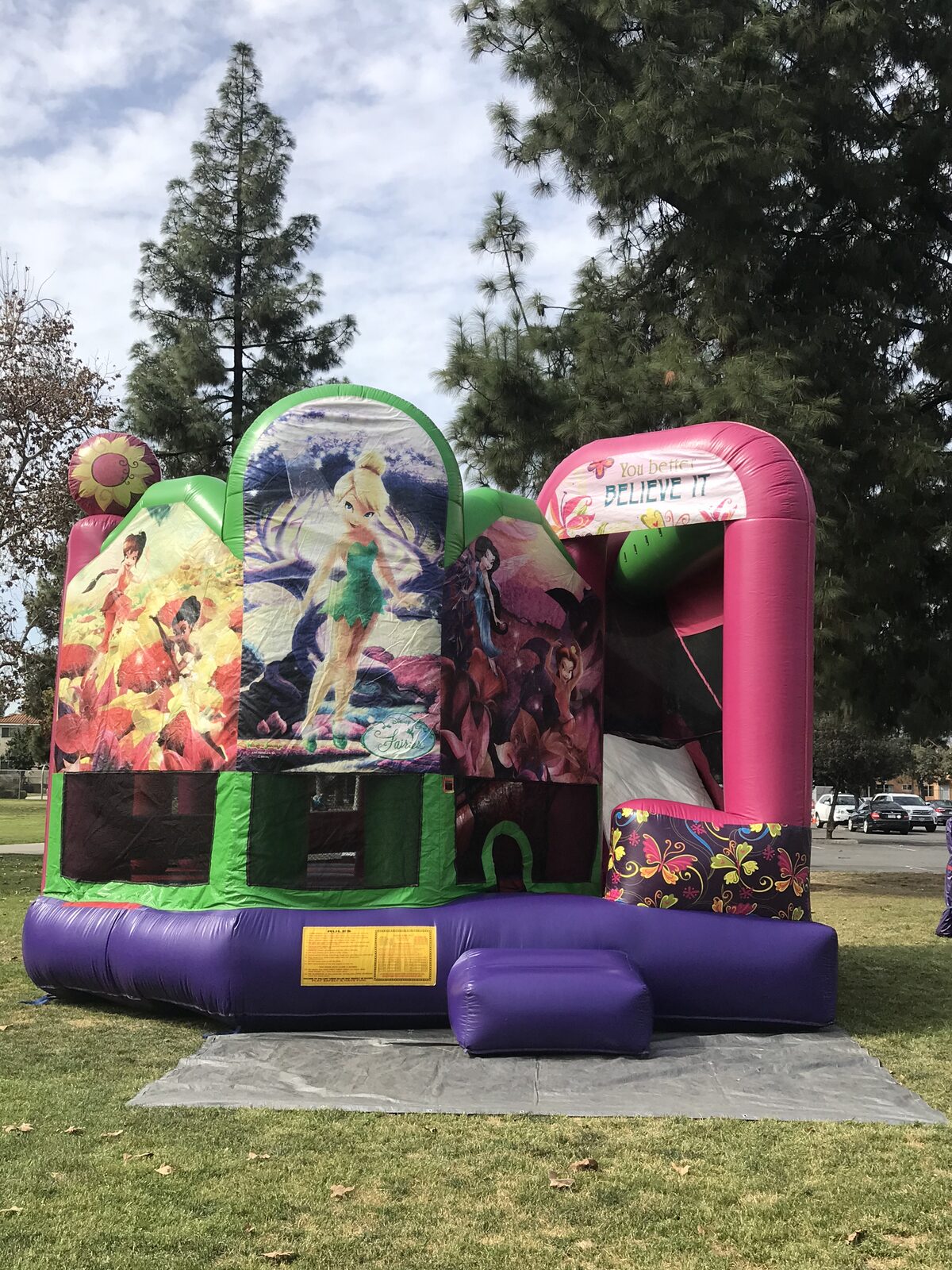 5n1 fairies combo bounce house rental in San Diego, three-quarter front view of the Tinker Bell art panels and Believe It arch on a tarp at a park