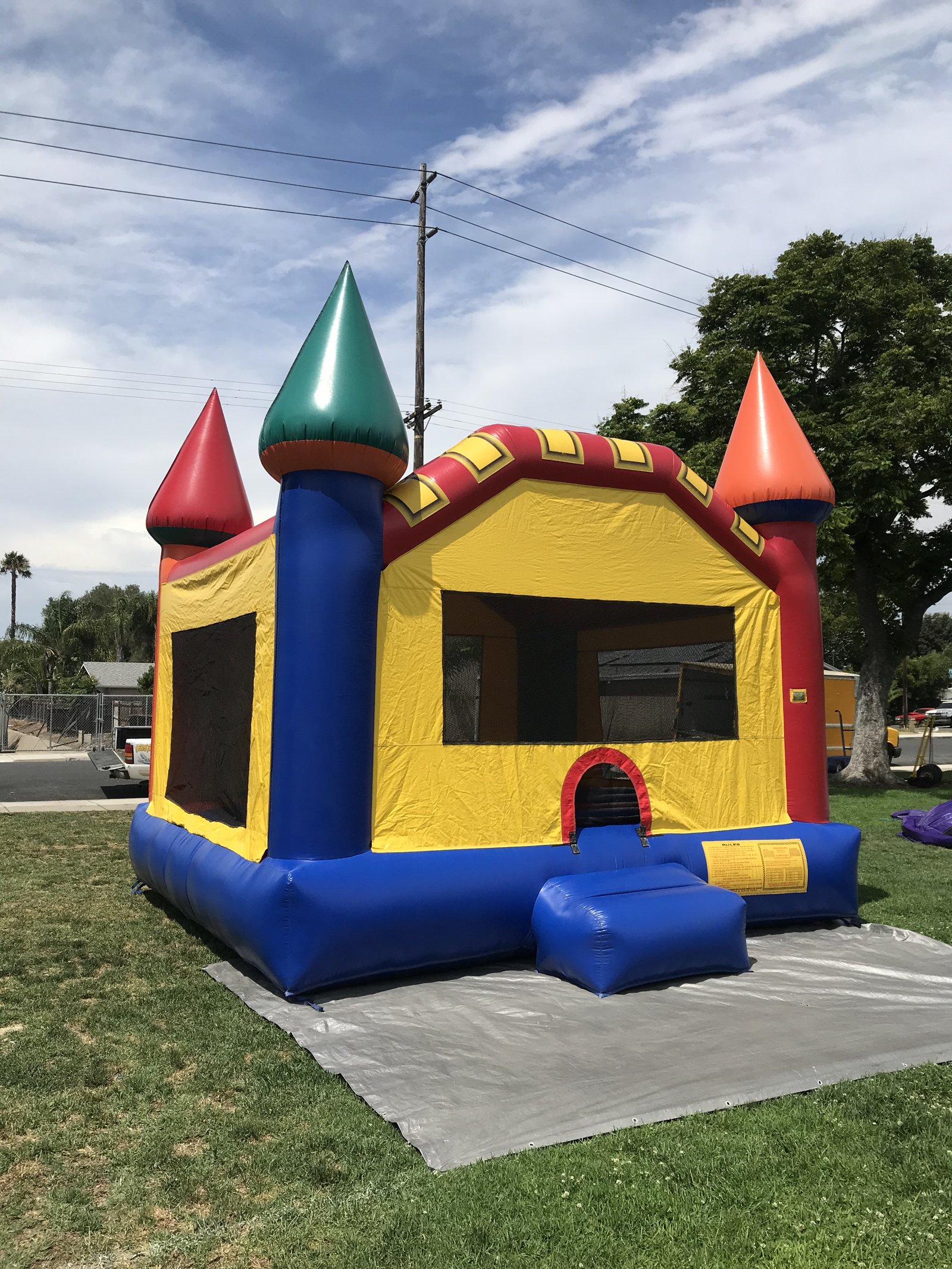 15x15 Multi-Color Castle bounce house rental in San Diego — side-angled view showing the large mesh safety windows and blue base