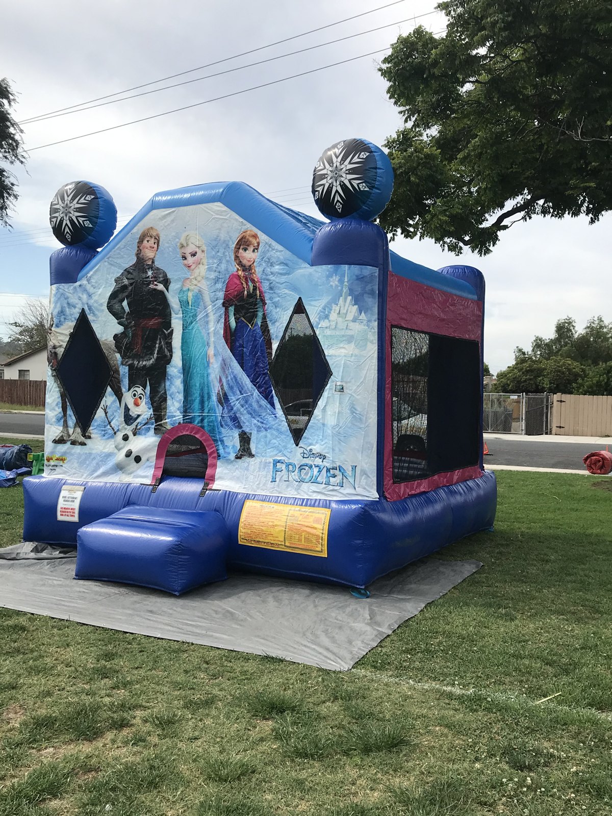 13x13 Frozen bounce house rental in San Diego — side-angled view set up on grass over a protective tarp