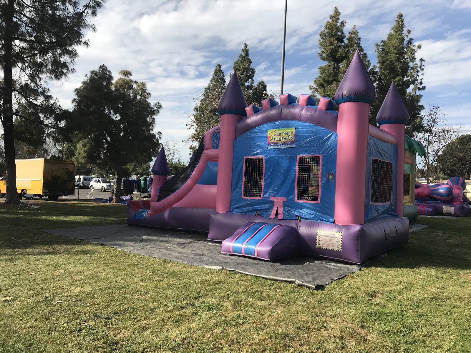 4n1 pink castle combo bounce house rental in San Diego, three-quarter front view of the blue walls, mesh windows, and pink turrets