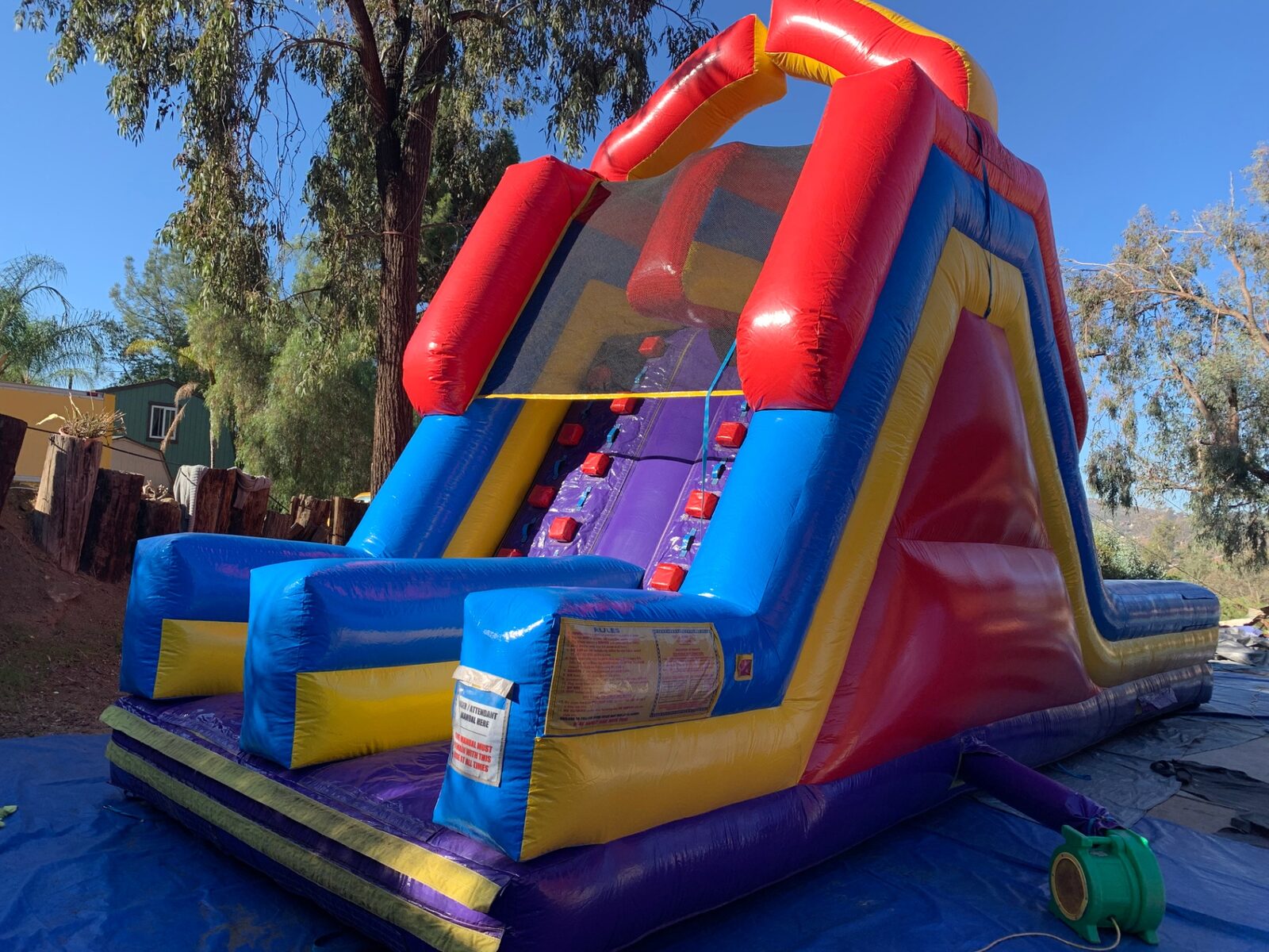 18ft dual lane monster obstacle course rental in San Diego, backyard setup showing the climb wall and attendant rules panel