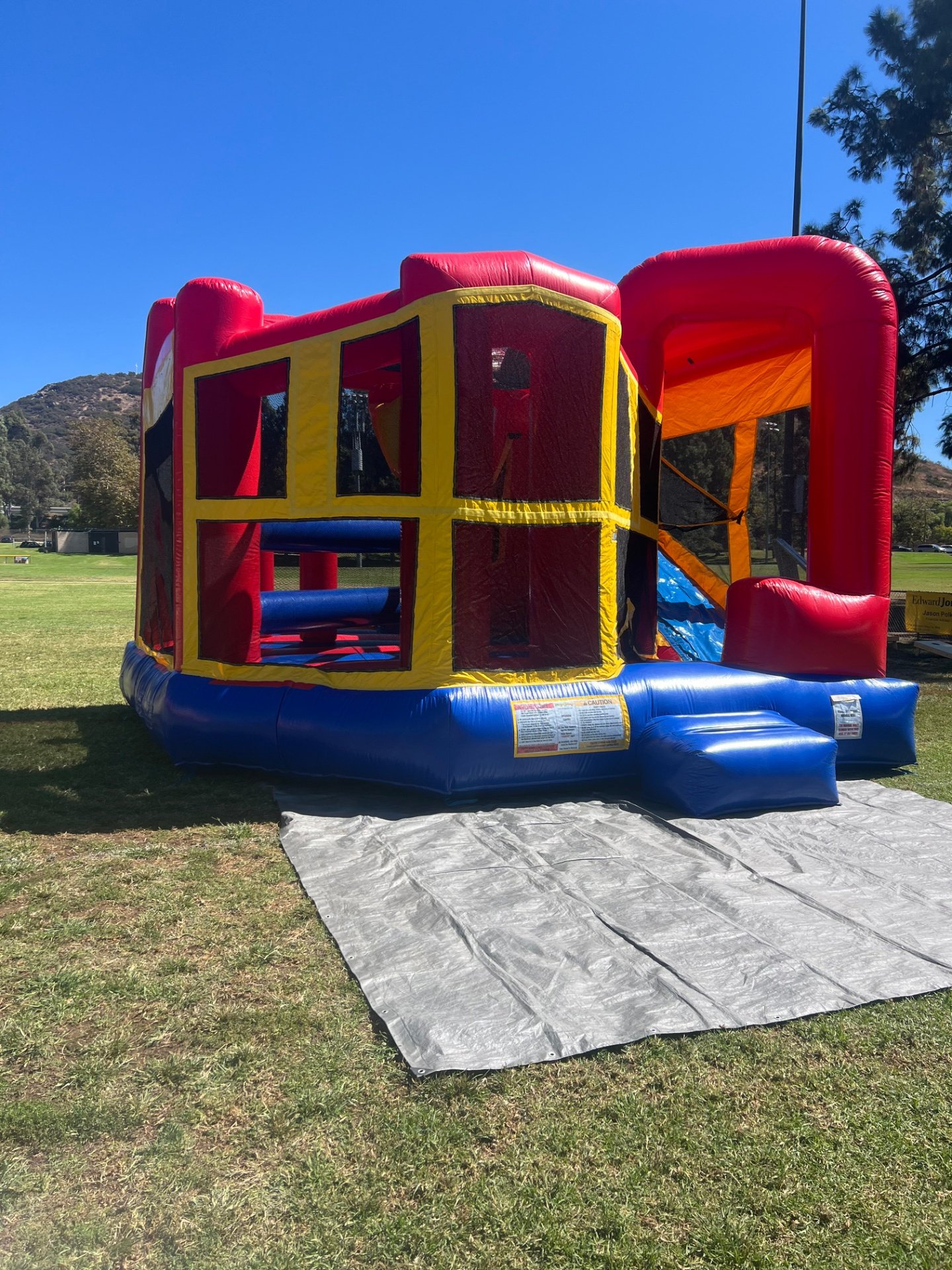 5n1 blue banner combo bounce house rental in San Diego, three-quarter view with the entry step and slide exit on a park field
