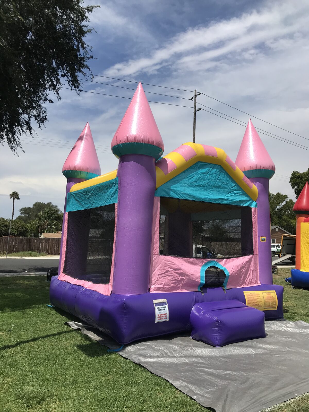 13x13 Dazzling Castle bounce house rental in San Diego — three-quarter view showing the mesh side windows and teal entry ramp