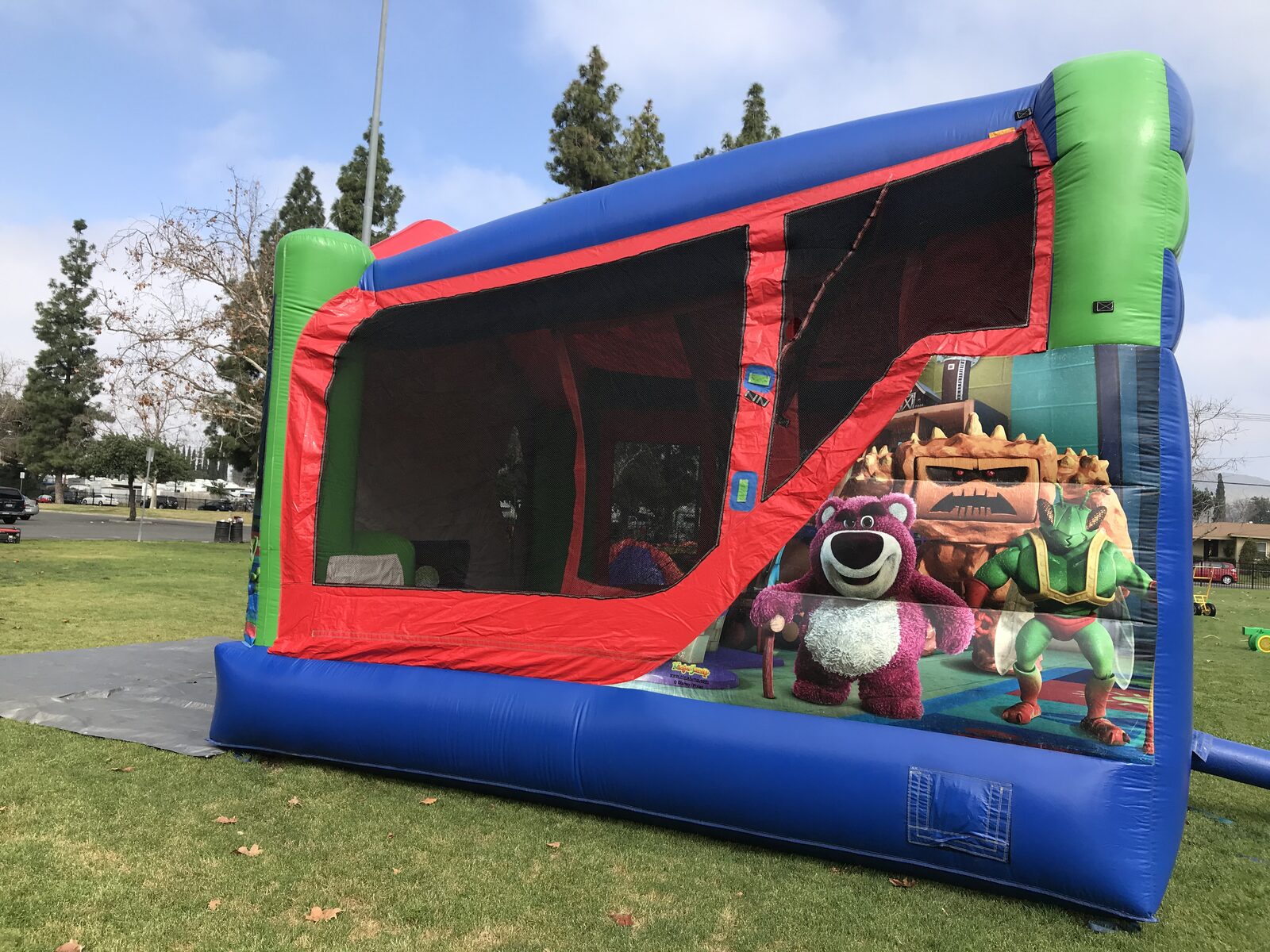 4n1 Toy Story combo bounce house rental in San Diego, angled side view showing the slide lane and Lotso and Rex art inside