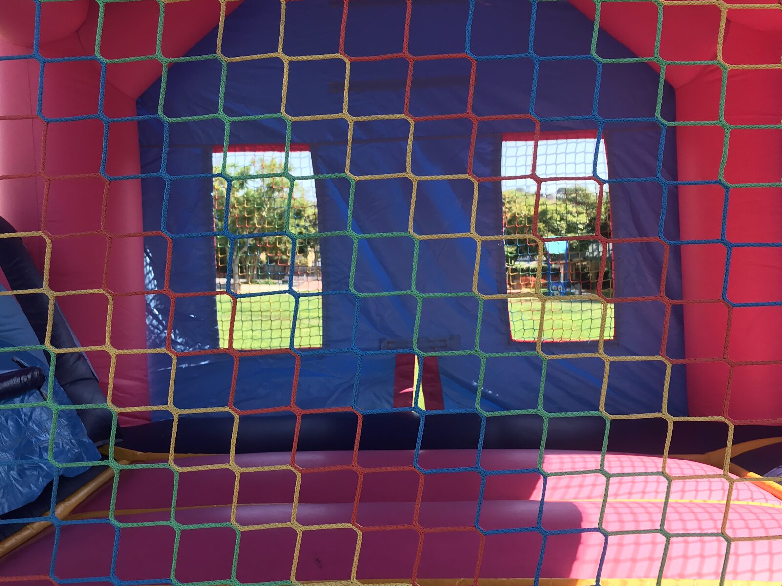2n1 pink princess combo bounce house rental in San Diego, inside view through the rainbow basketball netting toward the mesh windows