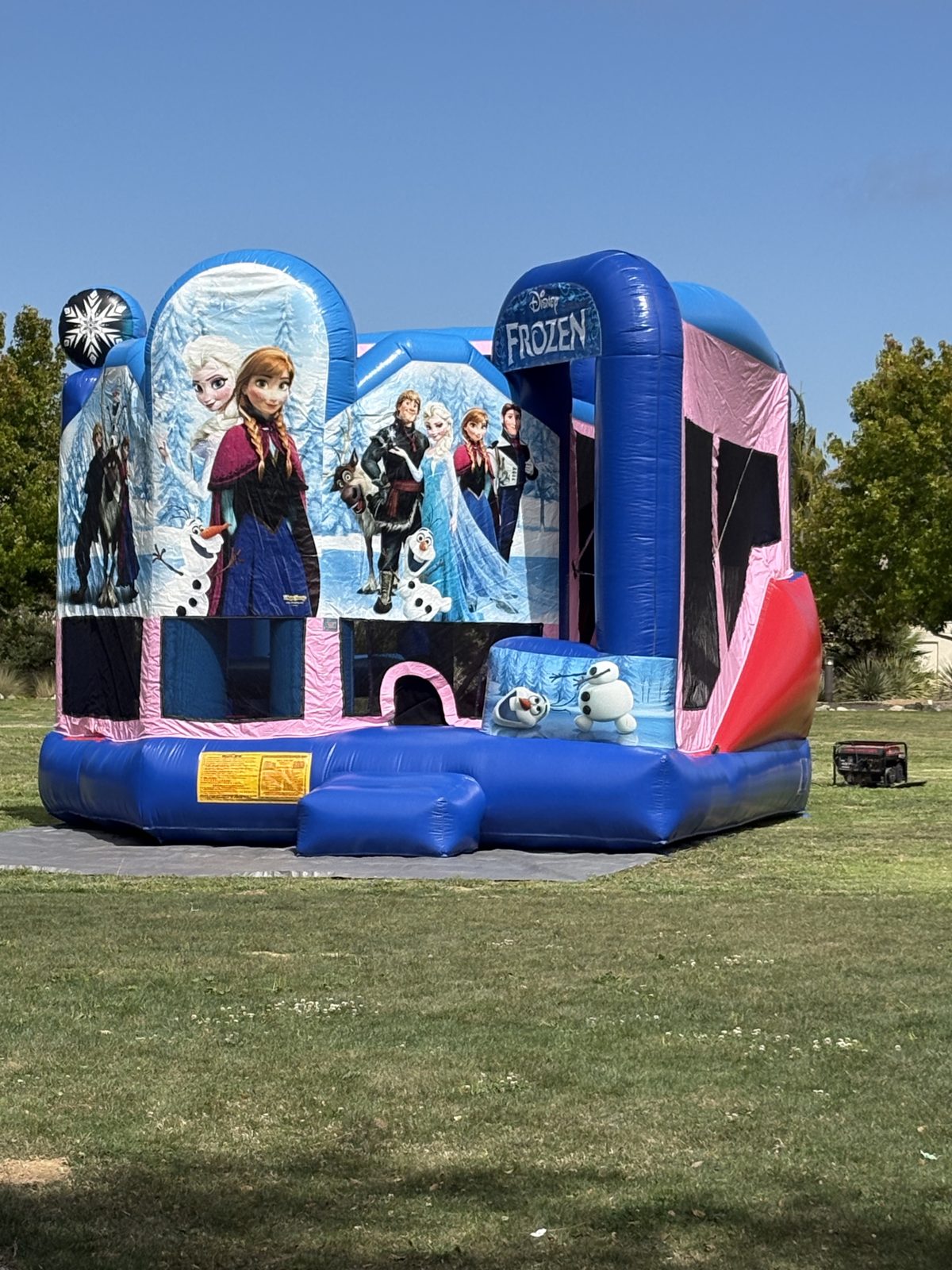 5n1 frozen combo bounce house rental in San Diego, full front view under a clear blue sky with the generator beside it
