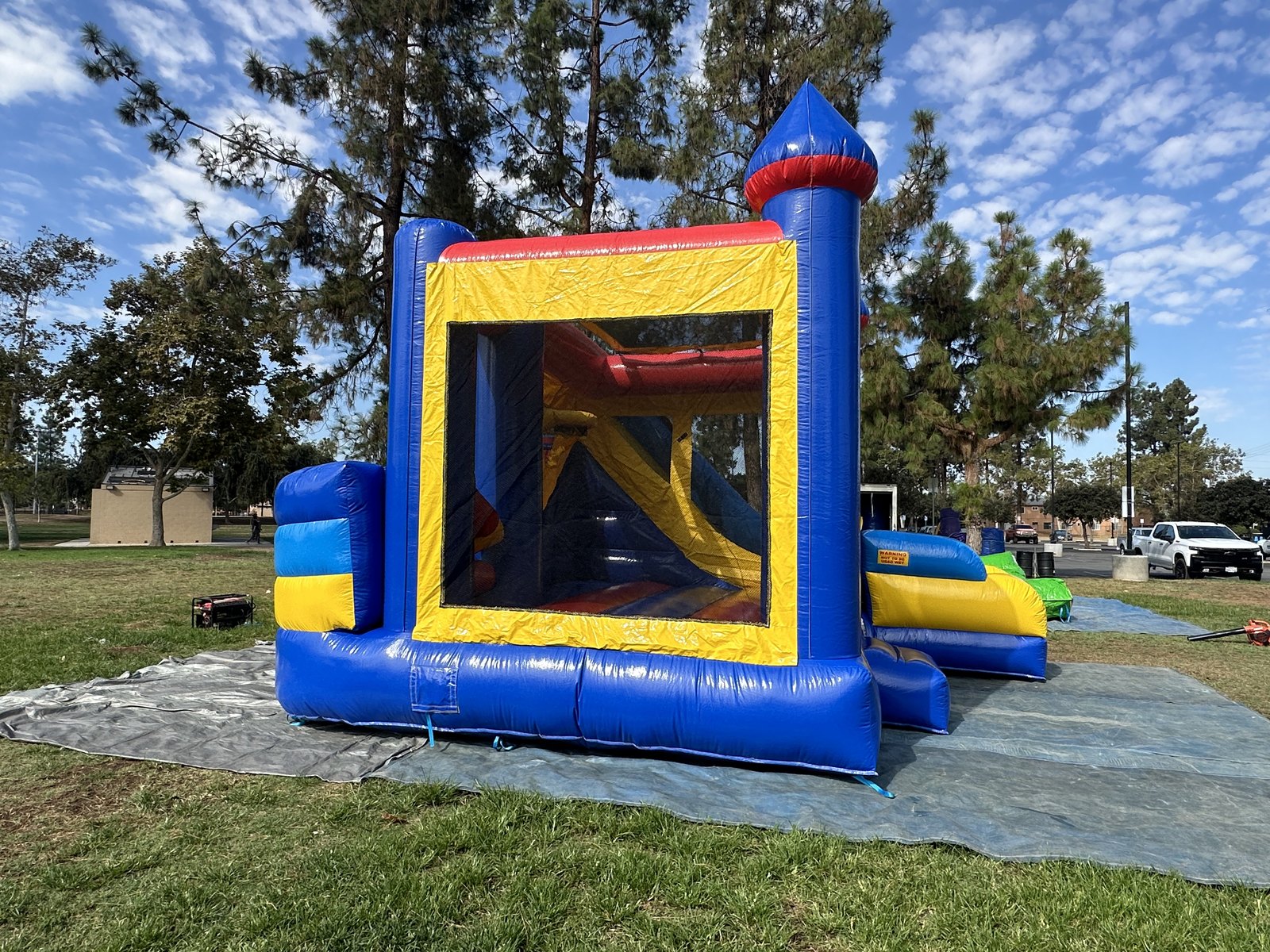 6n1 blue castle combo bounce house rental in San Diego, side view through the mesh window showing the inside climb-up and slide