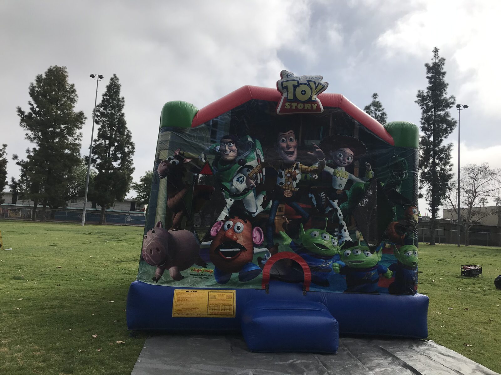 4n1 Toy Story combo bounce house rental in San Diego, front view of the Woody, Buzz and friends art panel on a tarp at a park