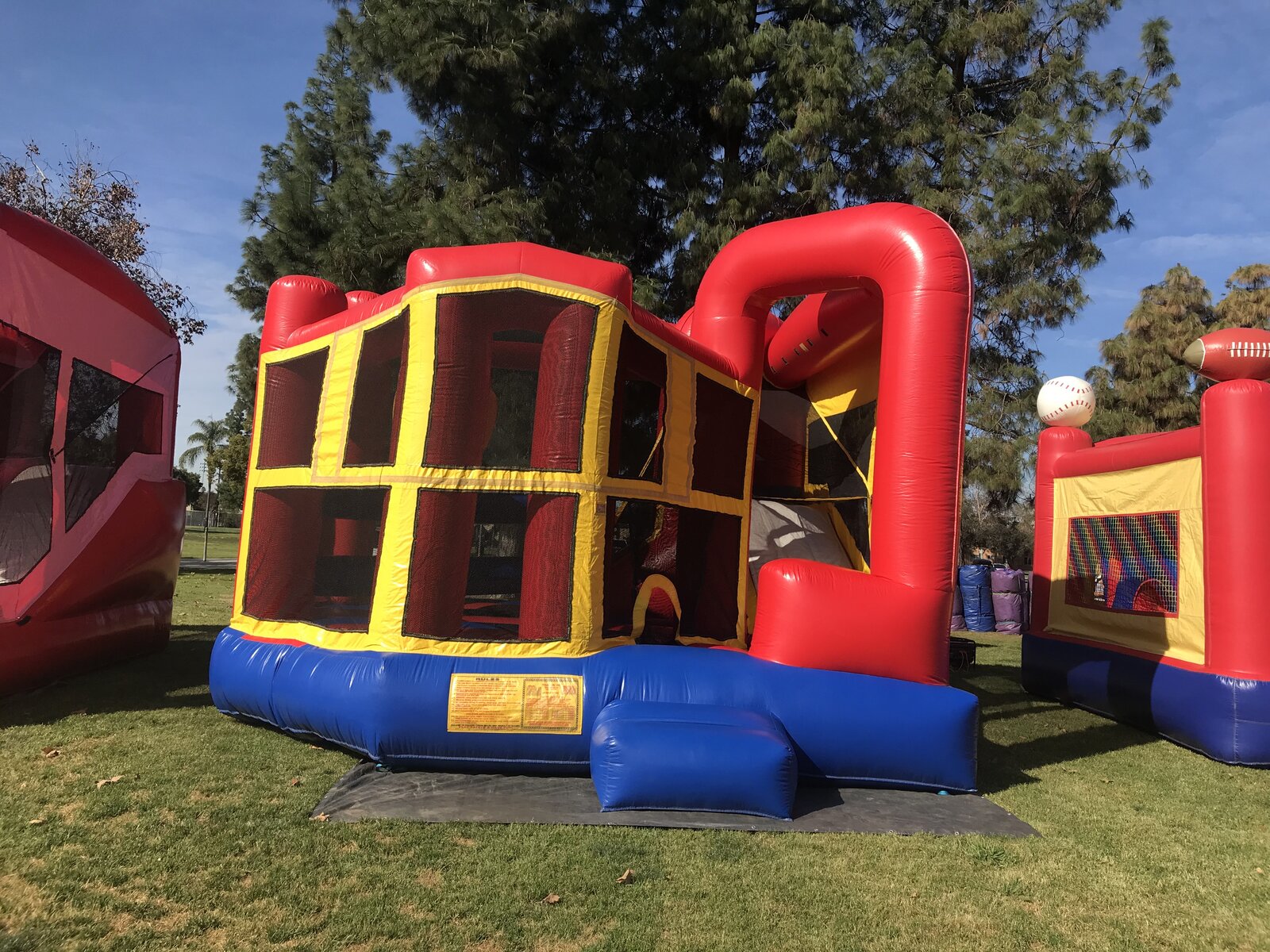 5n1 blue banner combo bounce house rental in San Diego, angled view of the jump area and slide tower at a shaded park setup