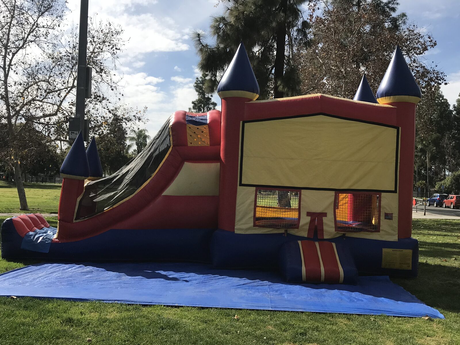 4n1 blue castle banner combo bounce house rental in San Diego, full side view of the unit staked on a tarp at a park