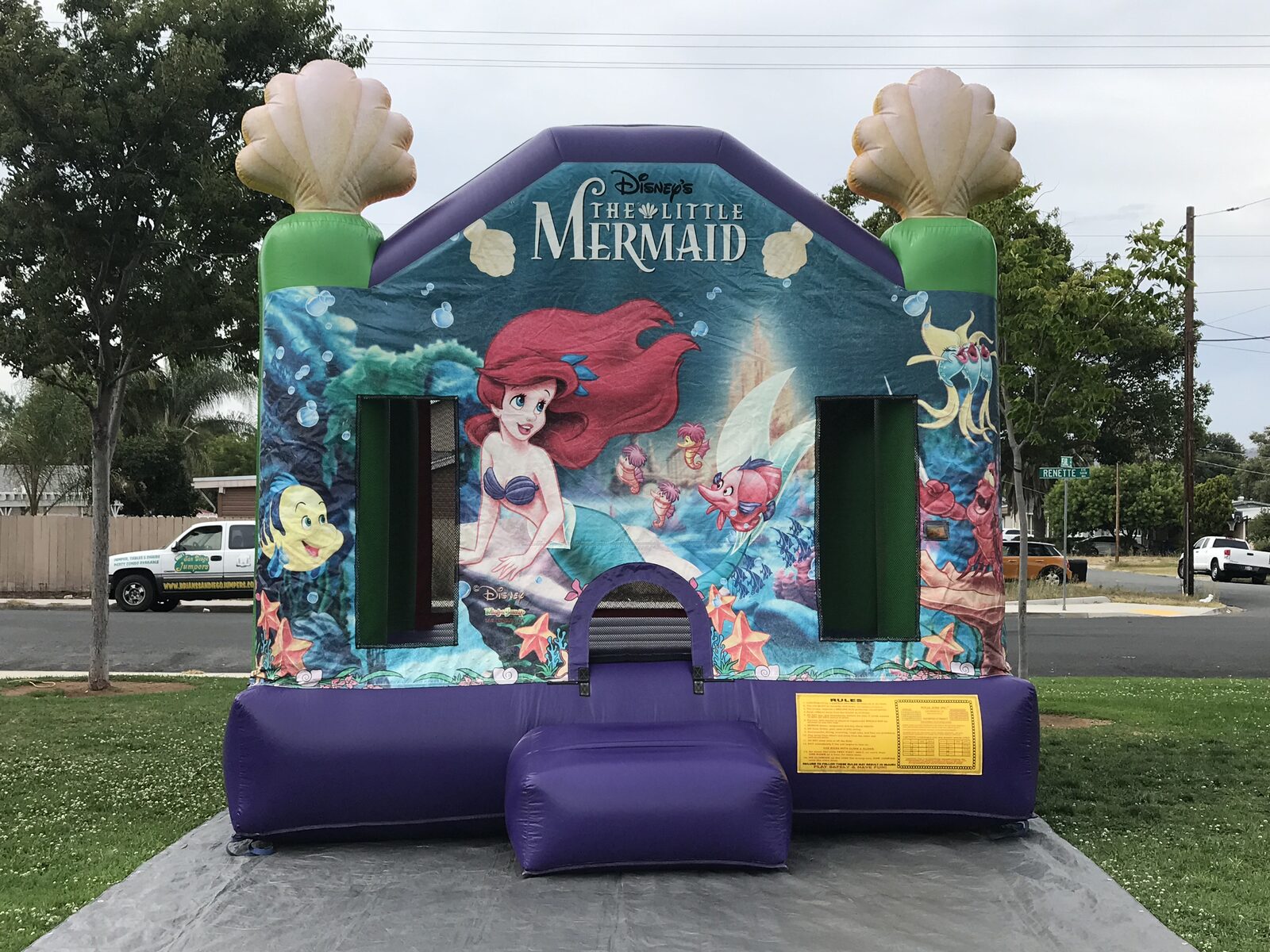 13x13 Ariel bounce house rental in San Diego — front view of the Disney Little Mermaid castle with Ariel, Flounder, and Sebastian artwork and seashell toppers