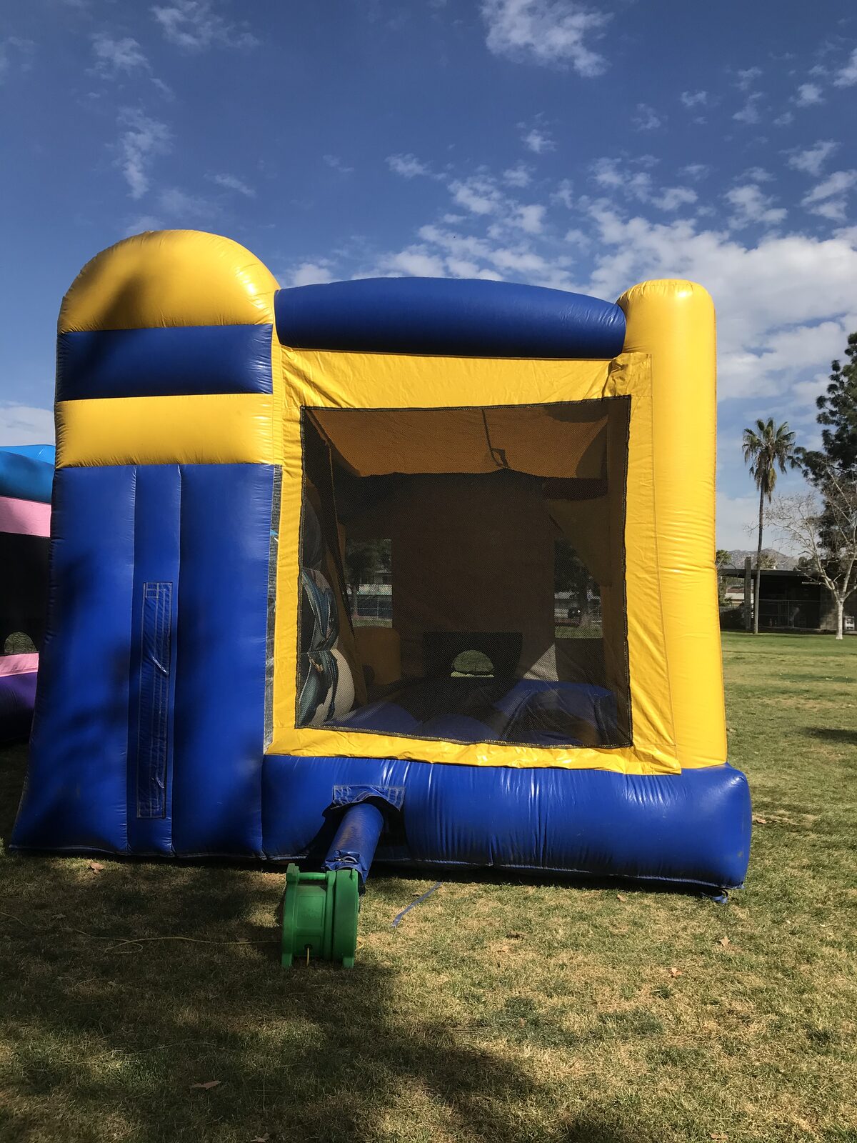 4n1 Batman combo bounce house rental in San Diego, rear corner view of the blue and yellow slide side with blower hooked up