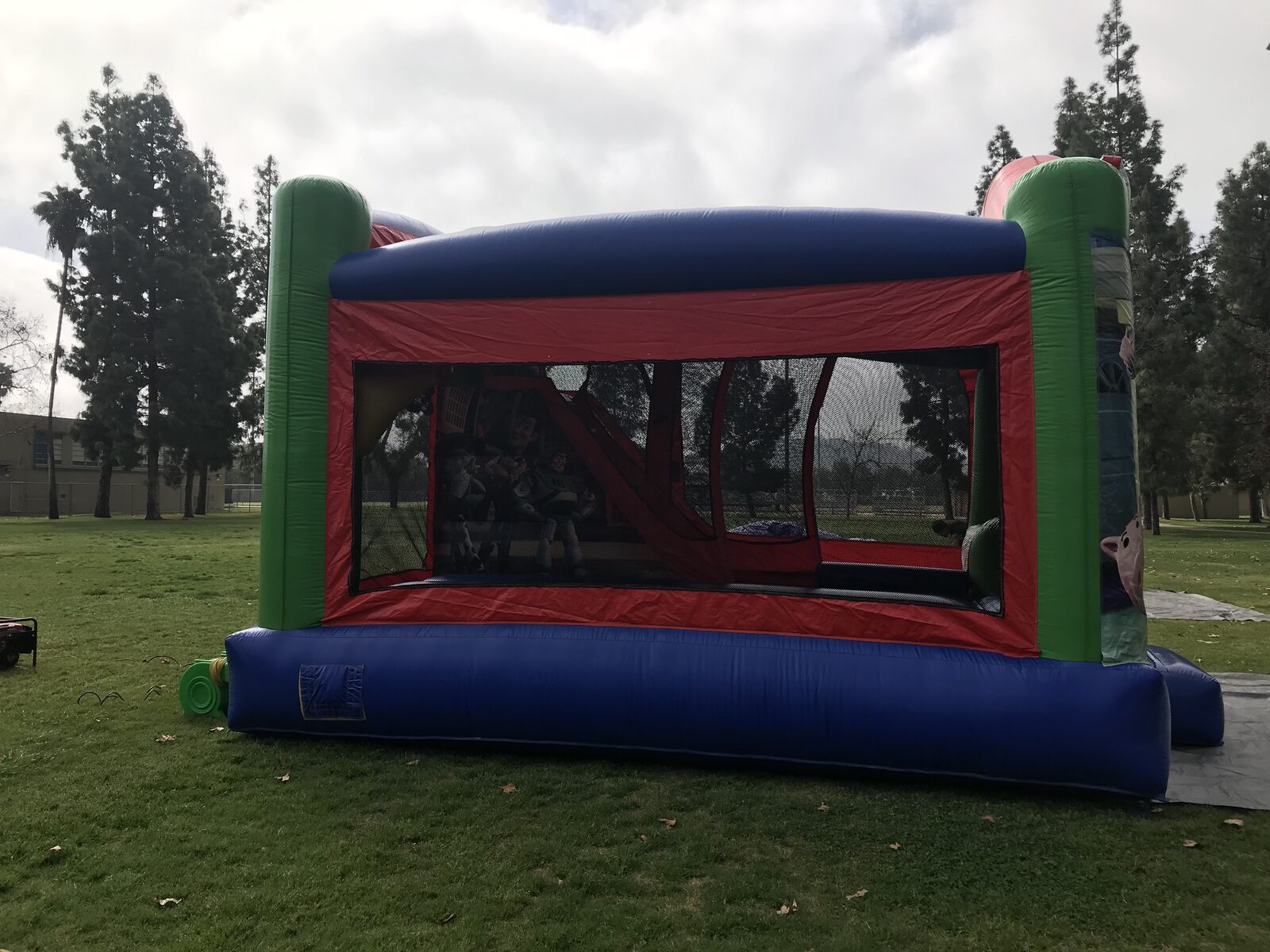 4n1 Toy Story combo bounce house rental in San Diego, side view of the red, blue and green unit with full mesh windows