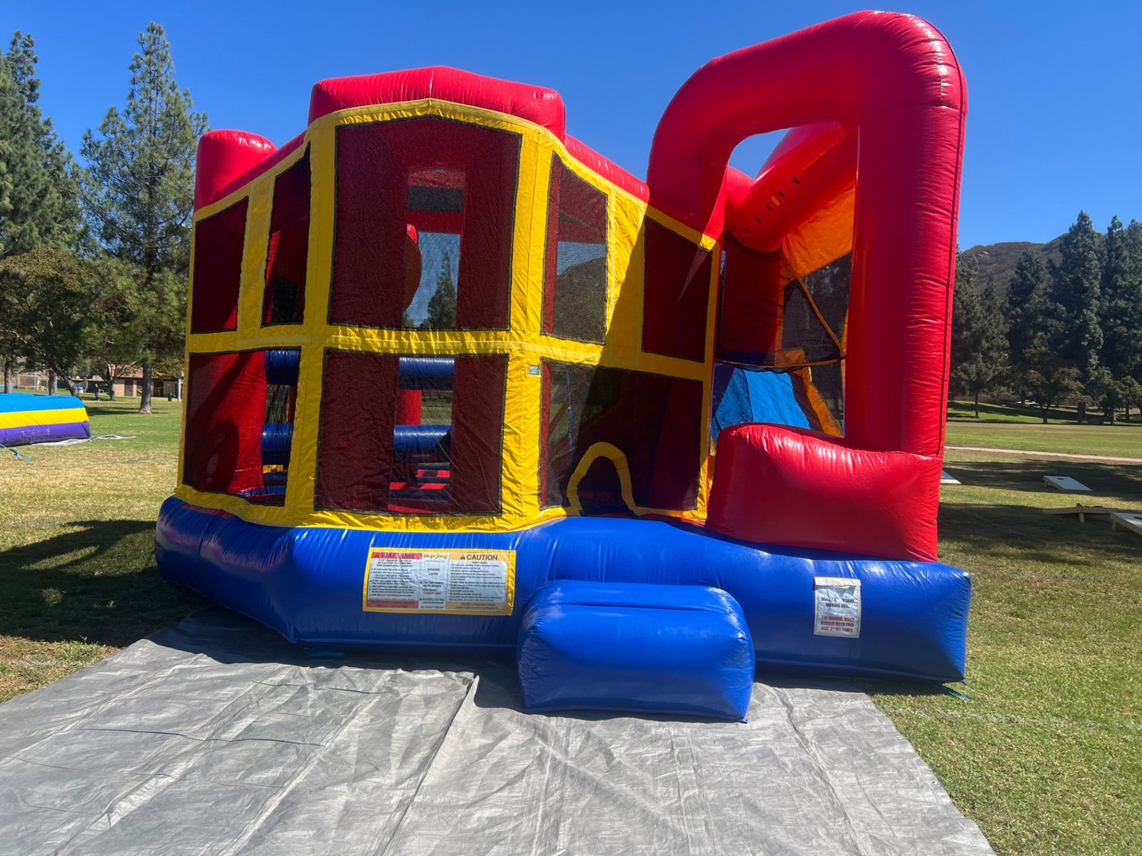 5n1 blue banner combo bounce house rental in San Diego, wide front view staked on a tarp under a clear blue sky