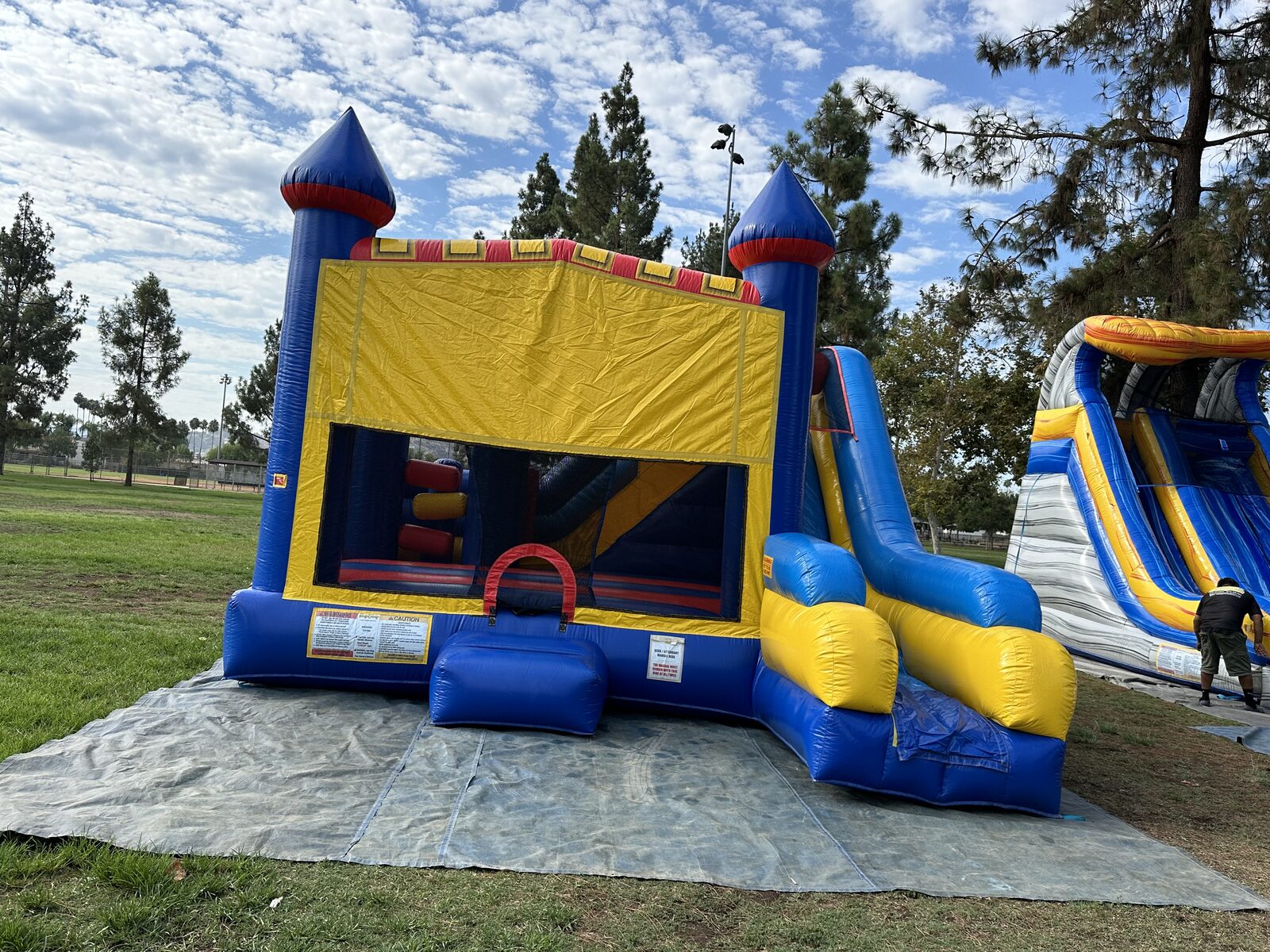 6n1 blue castle banner combo bounce house rental in San Diego, straight-on front view of the yellow banner panel, mesh entry window and slide