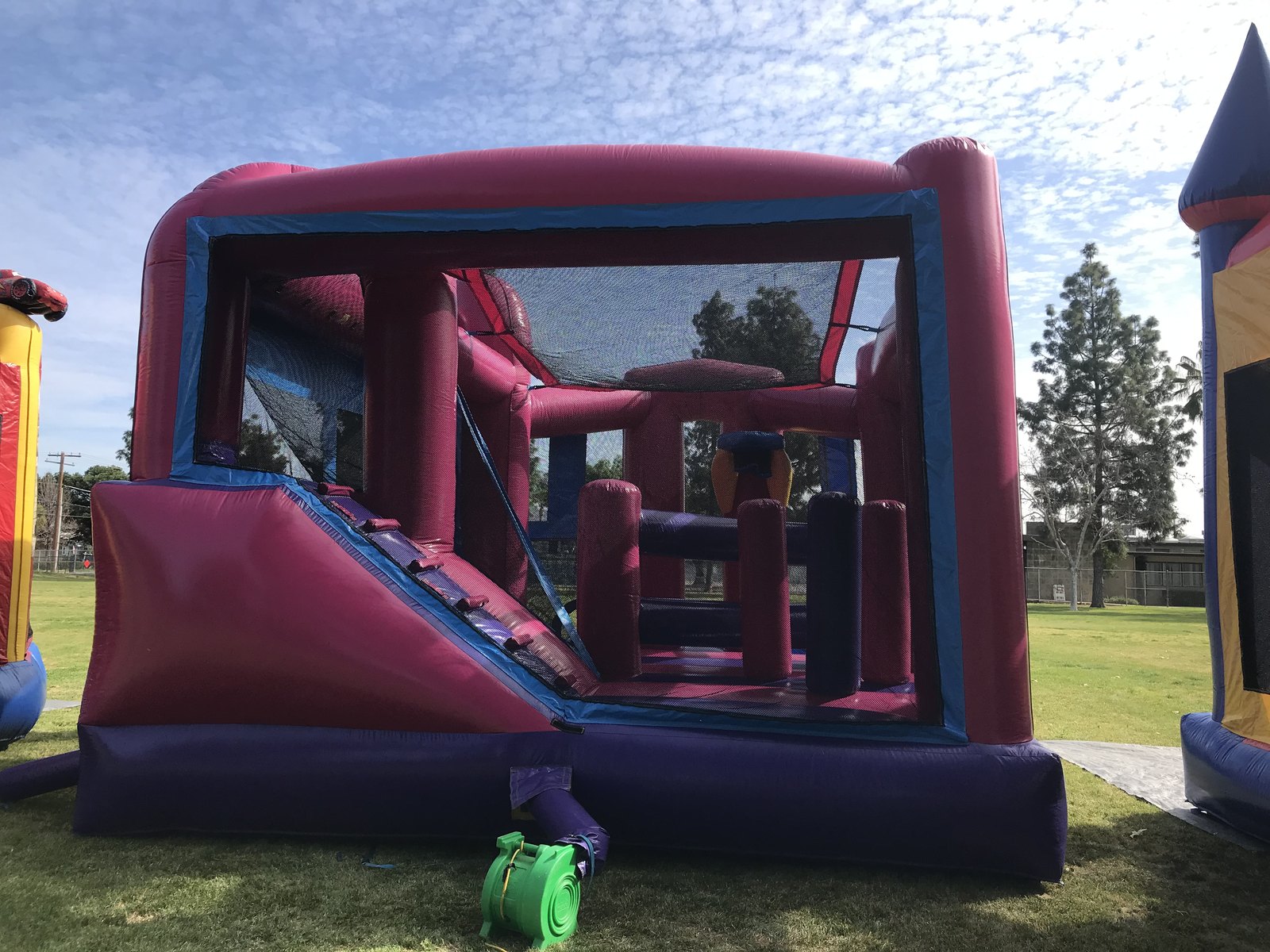 5n1 pink banner combo bounce house rental in San Diego, open front view showing the slide, jump area and padded obstacle columns inside