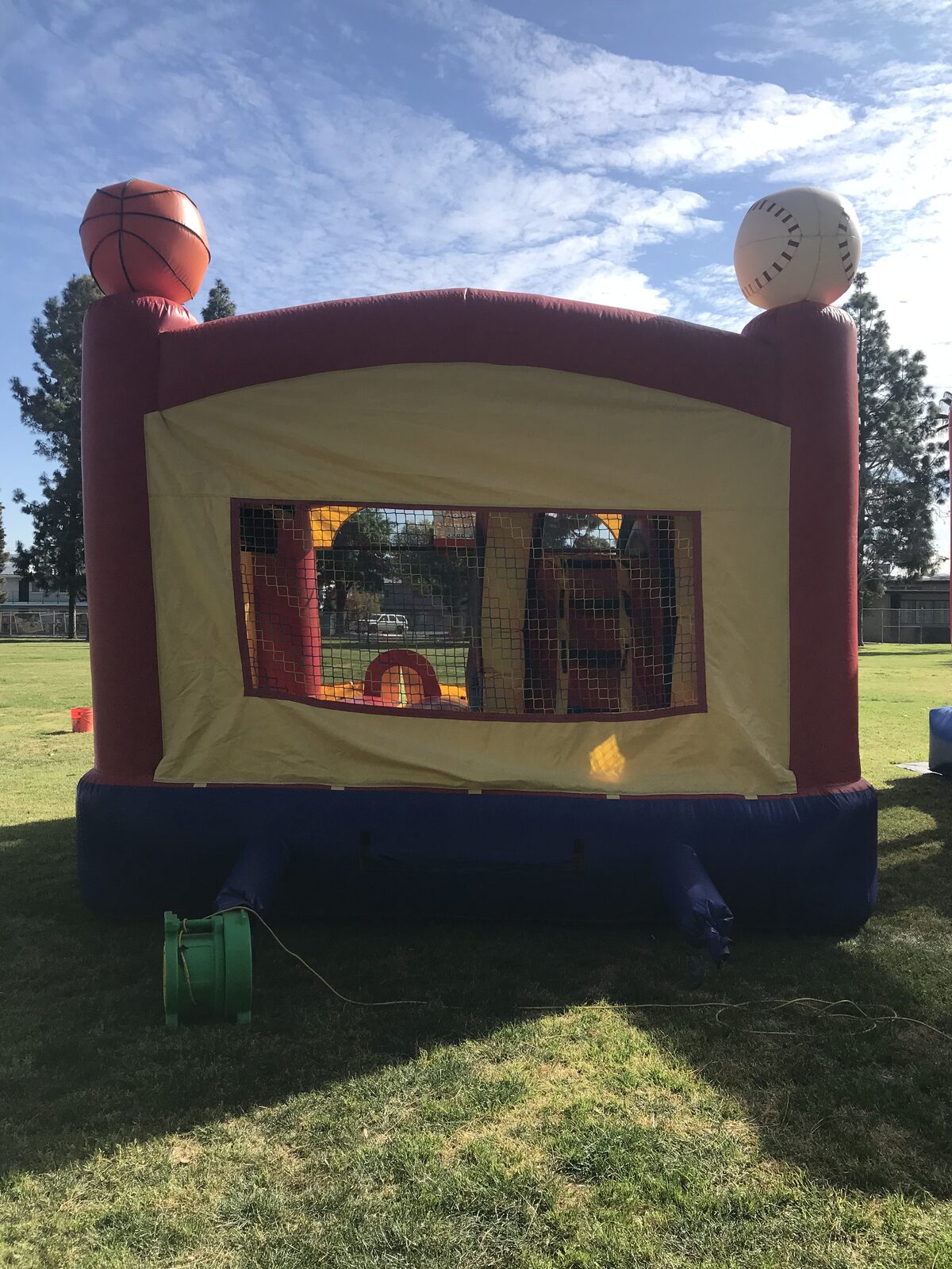 5n1 sports combo bounce house rental in San Diego, side view showing the basketball and baseball toppers, mesh viewing window, and green blower