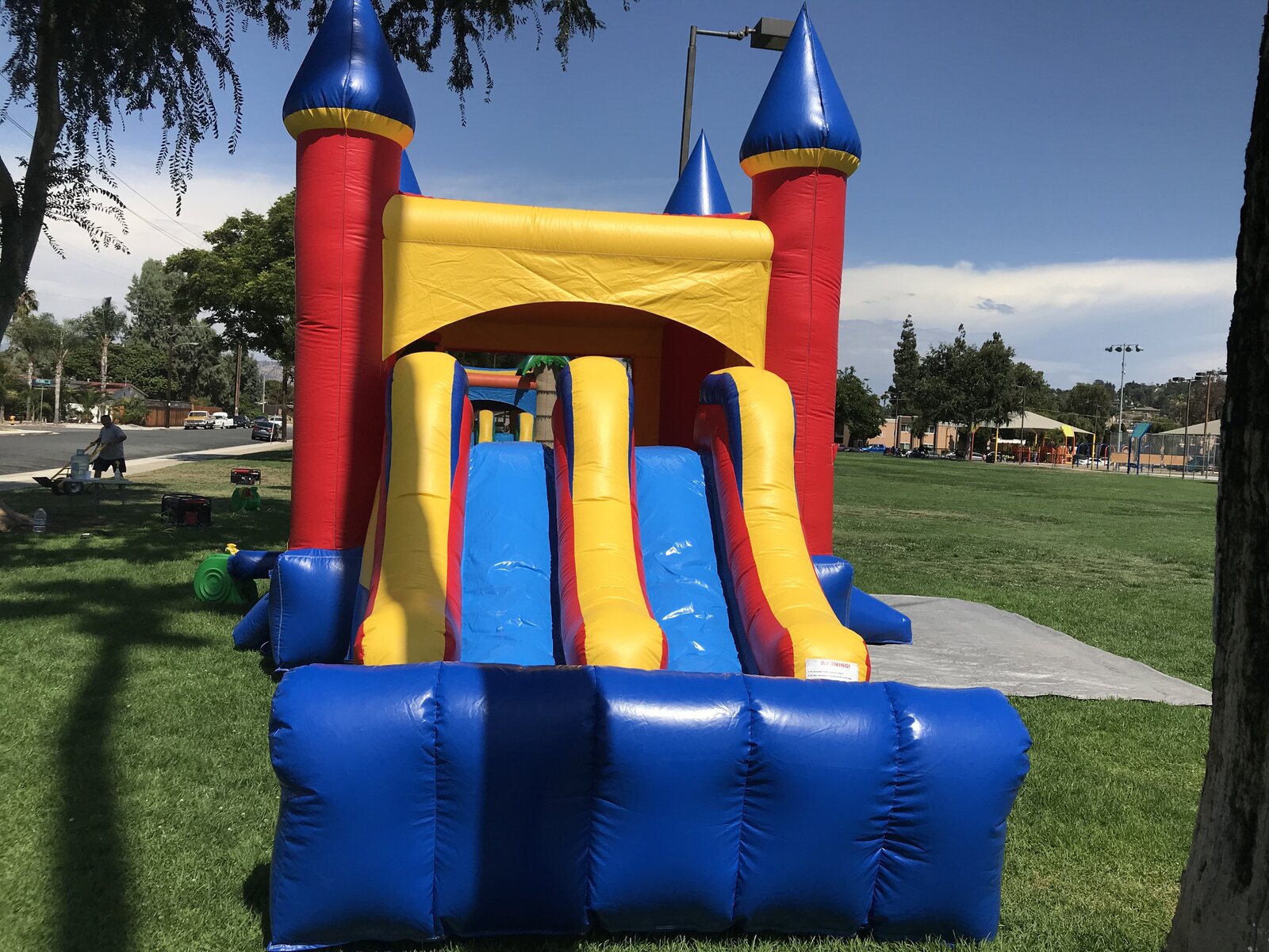 3n1 blue castle banner combo bounce house rental in San Diego, wide view of both slide lanes with the park and playground in the background