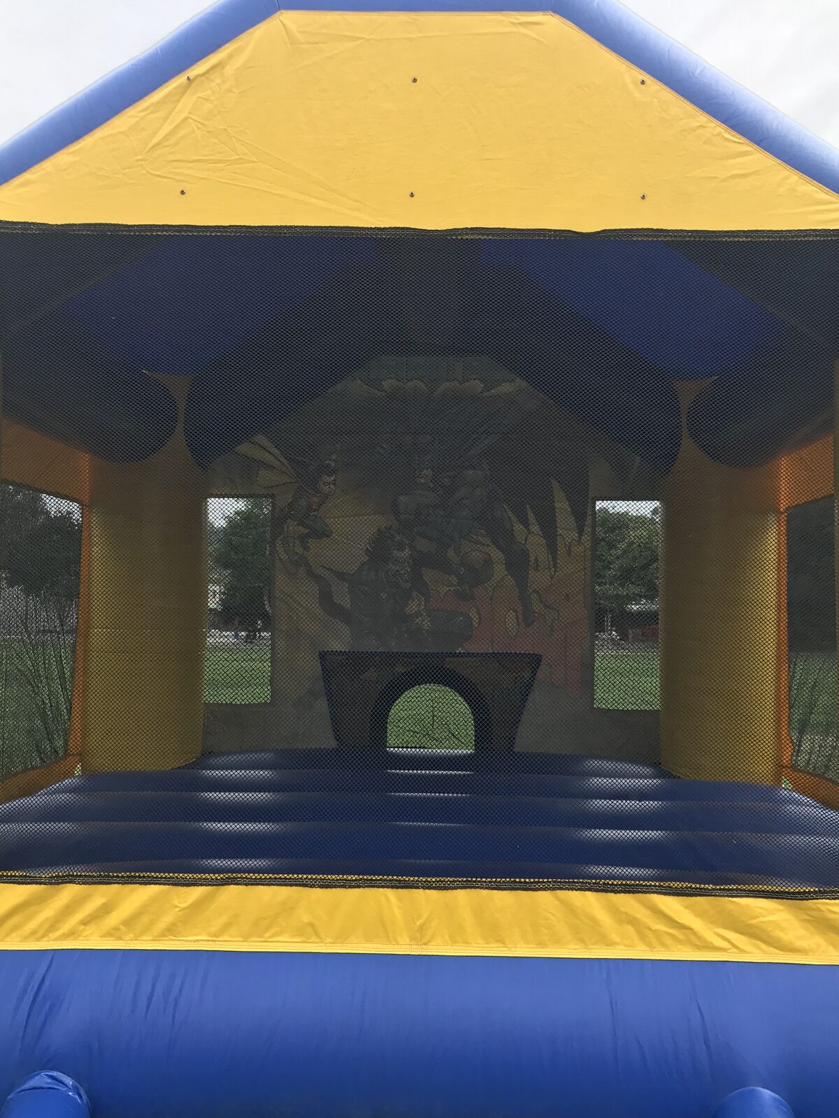 13x13 Batman bounce house rental in San Diego — inside view of the blue jumping floor, basketball hoop, and mesh safety netting
