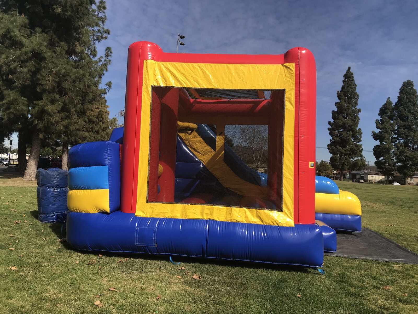 6n1 banner combo bounce house rental in San Diego, rear view of the unit staked down on grass