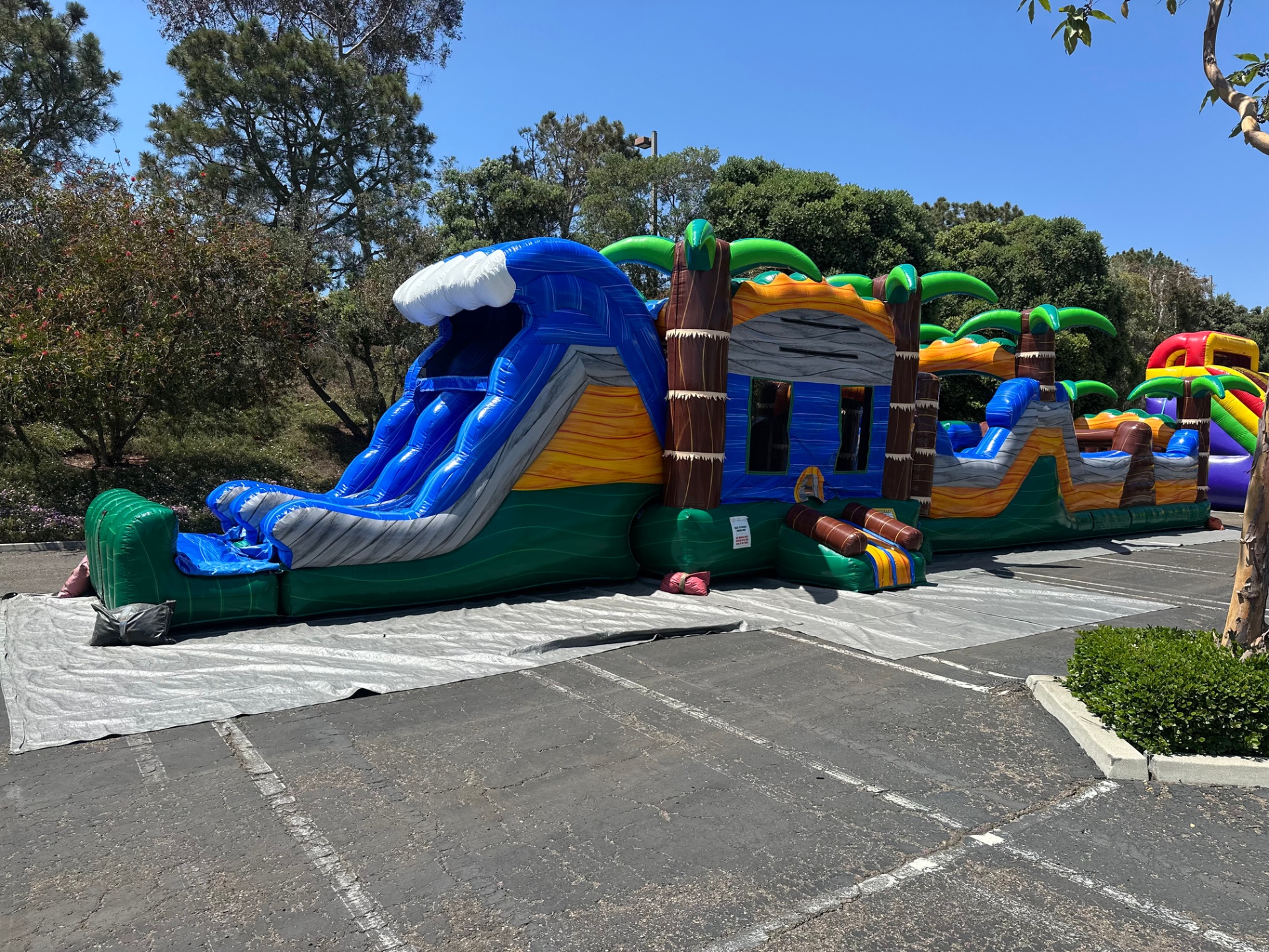 63ft tropical obstacle course rental in San Diego, tall blue wave slide exit at the end of the course