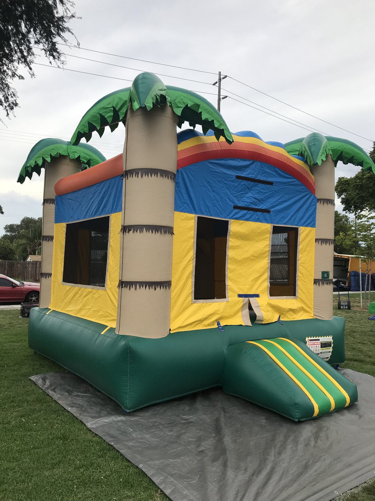 13x13 Palm Tree bounce house rental in San Diego — rear-angled view set up on grass over a protective tarp