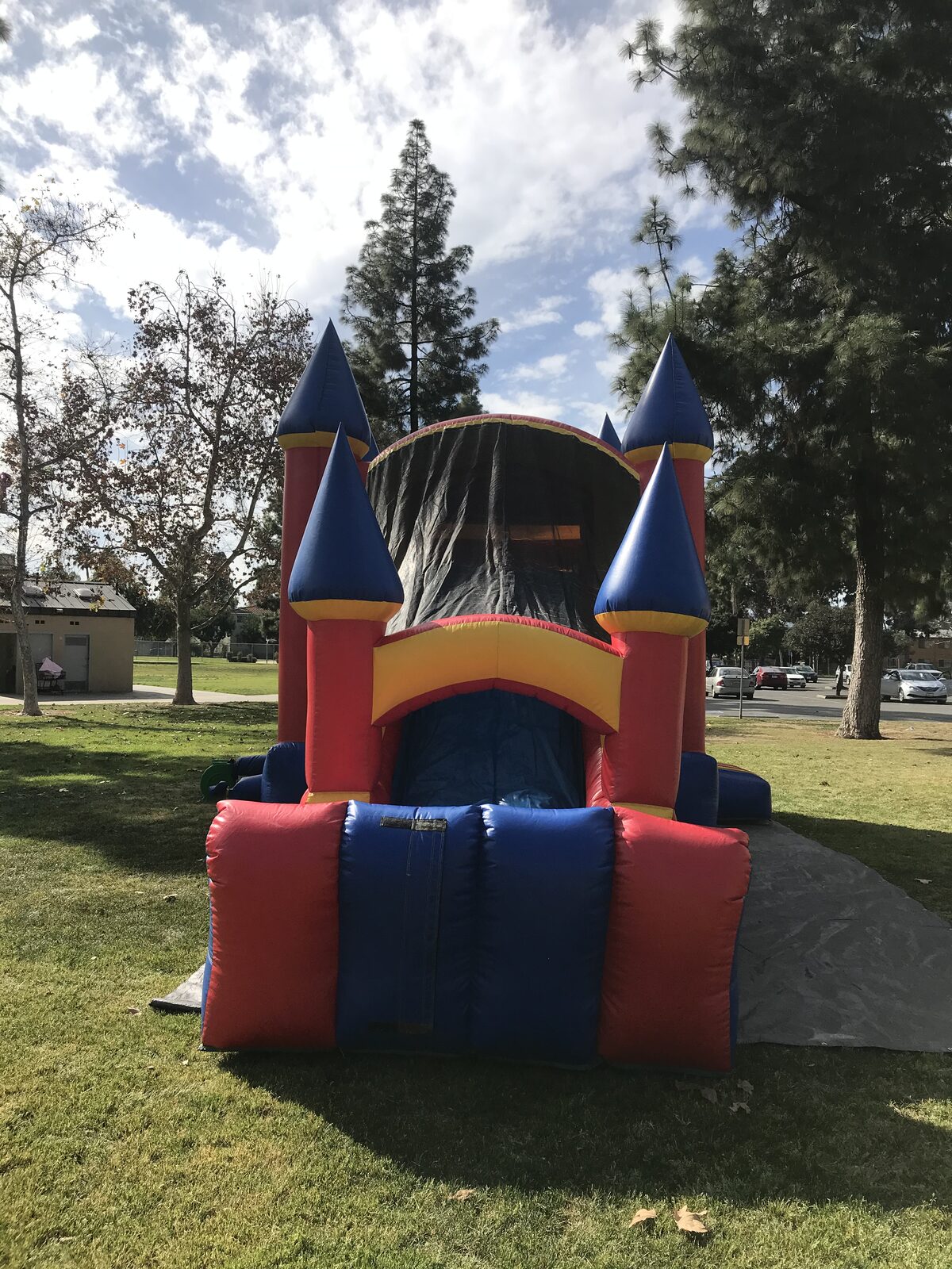 4n1 blue castle combo bounce house rental in San Diego, head-on view of the slide exit framed by blue-topped towers
