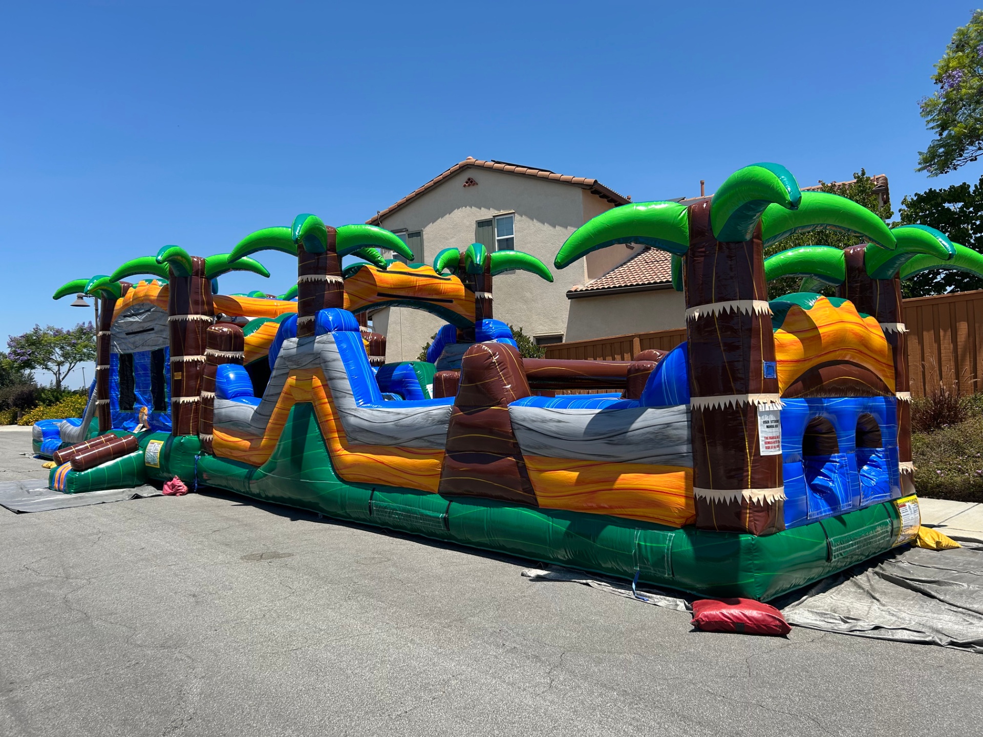63ft tropical obstacle course rental in San Diego, three-quarter view of the palm trees and interior obstacle lane