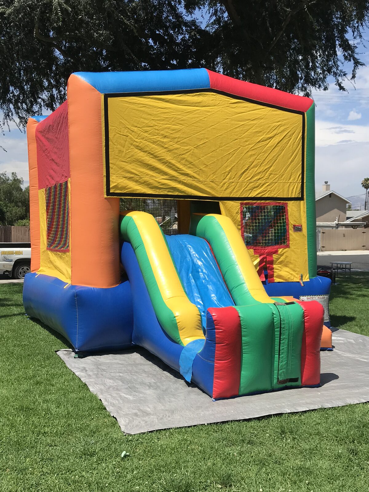 2n1 multi color castle banner combo bounce house rental in San Diego, angled view of the green, orange, and blue walls with the front slide
