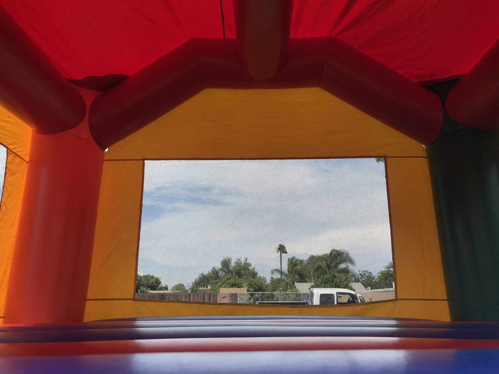 15x15 Multi-Color Castle bounce house rental in San Diego — inside view of the jumping floor looking out the large mesh safety window